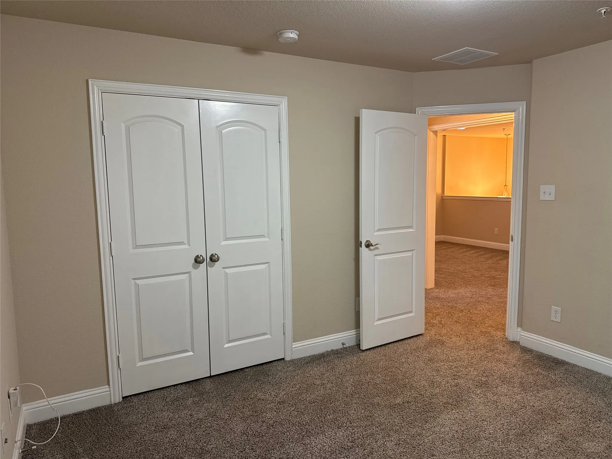 Bedroom featuring neutral carpeting, light beige wall paint, white baseboards, and a white bi-fold closet door