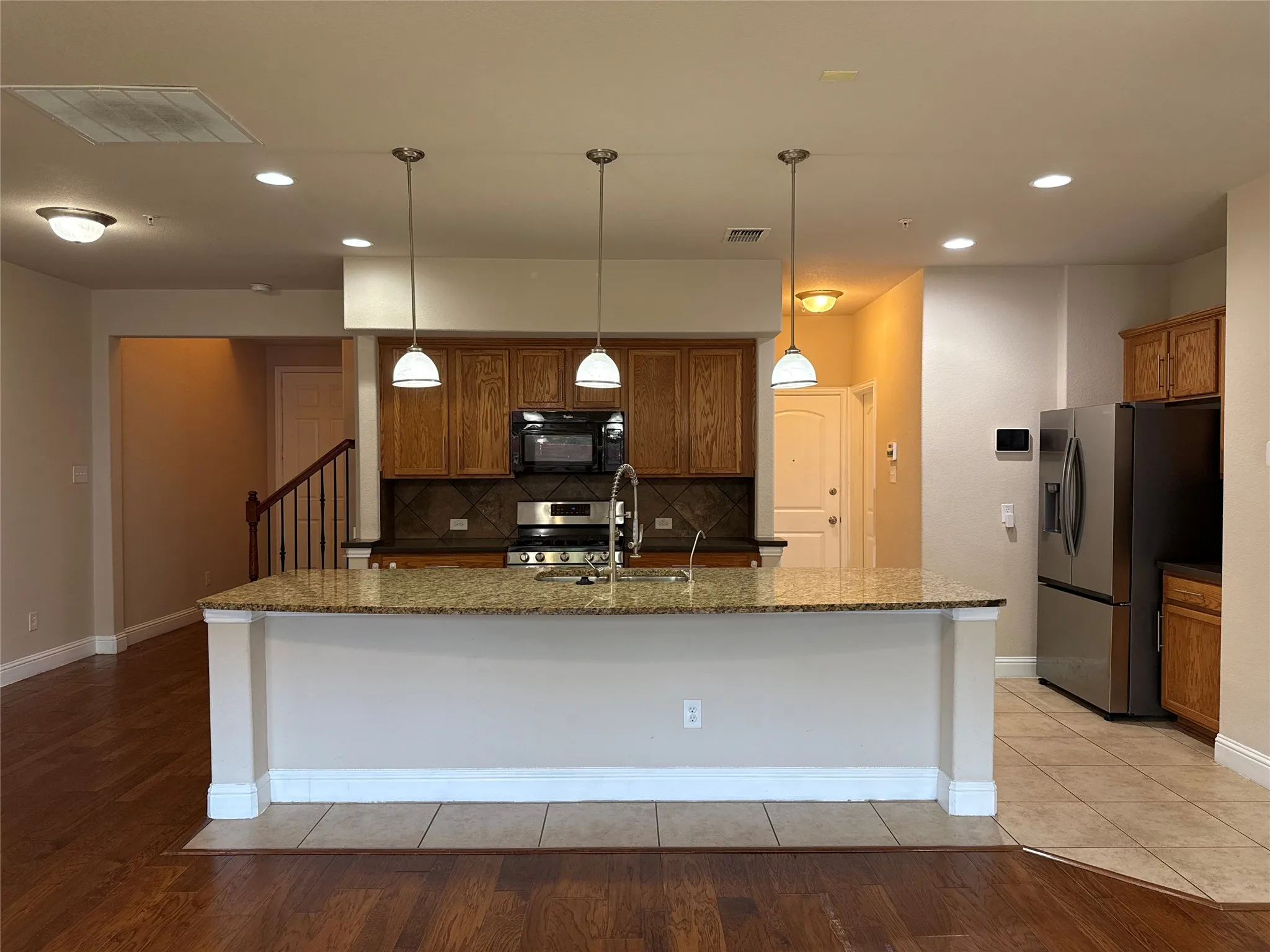 Kitchen island with granite countertop and integrated sink, complemented by three pendant lights