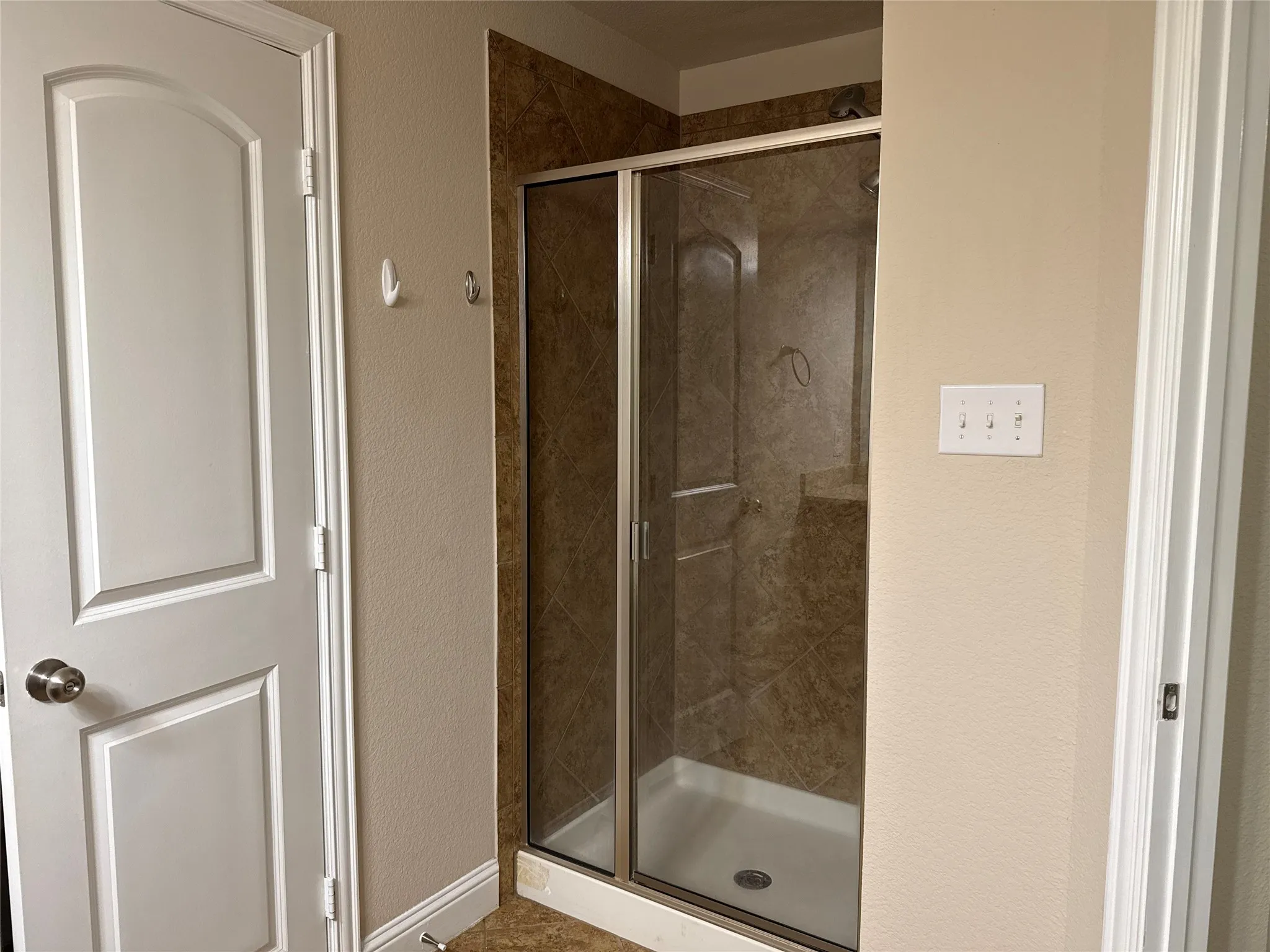 Glass-enclosed shower with a tiled surround, integrated shelf, and white shower base