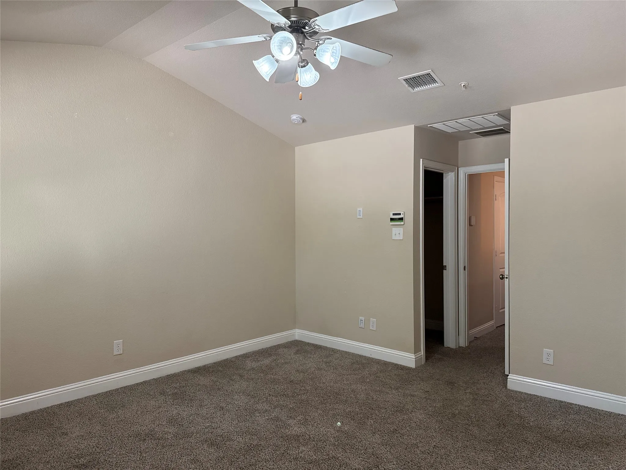 Carpeted room featuring a vaulted ceiling and a ceiling fan with integrated lighting