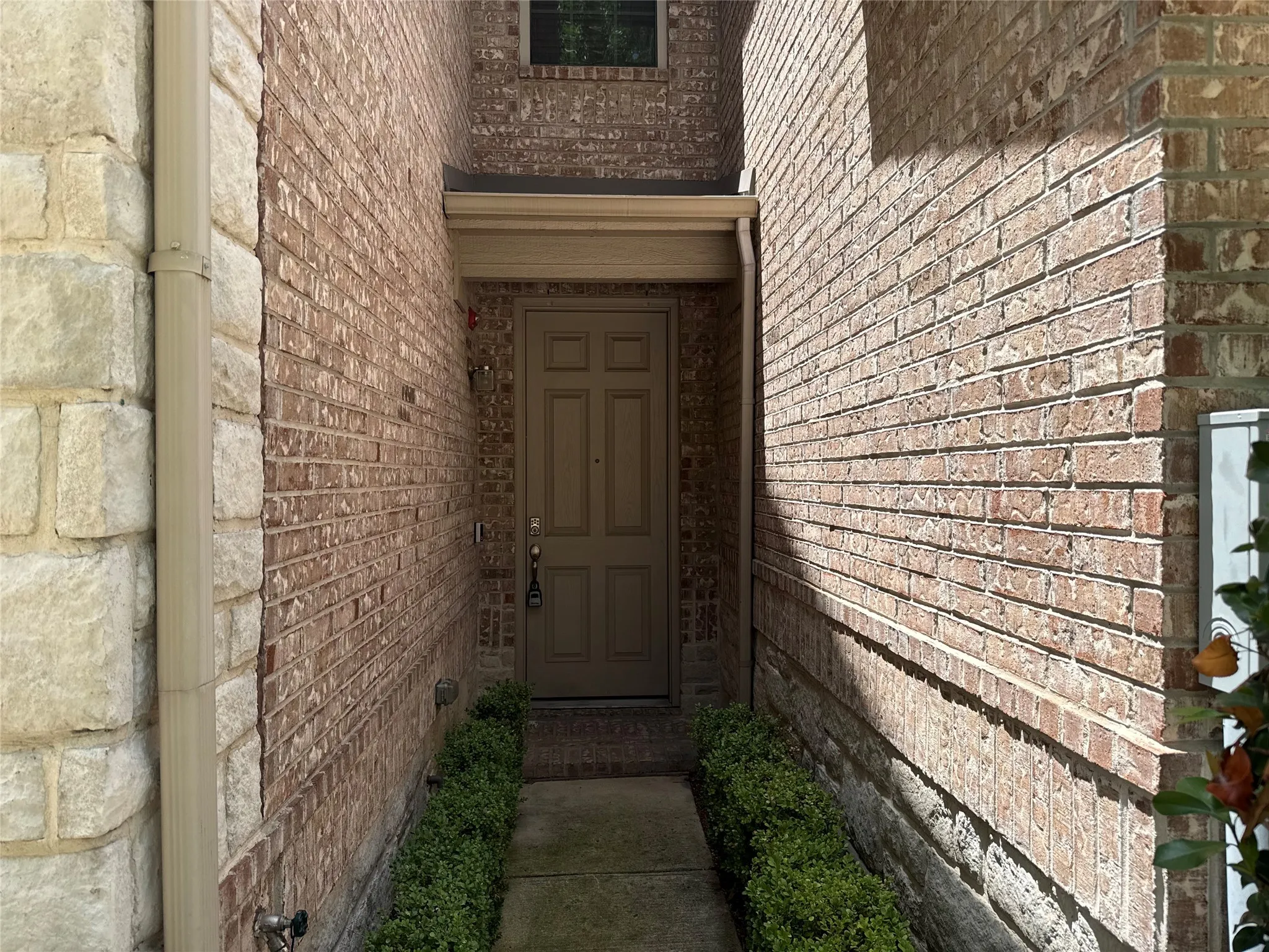 Front entry featuring a panel door, brick facade, stone accents, and a covered portico