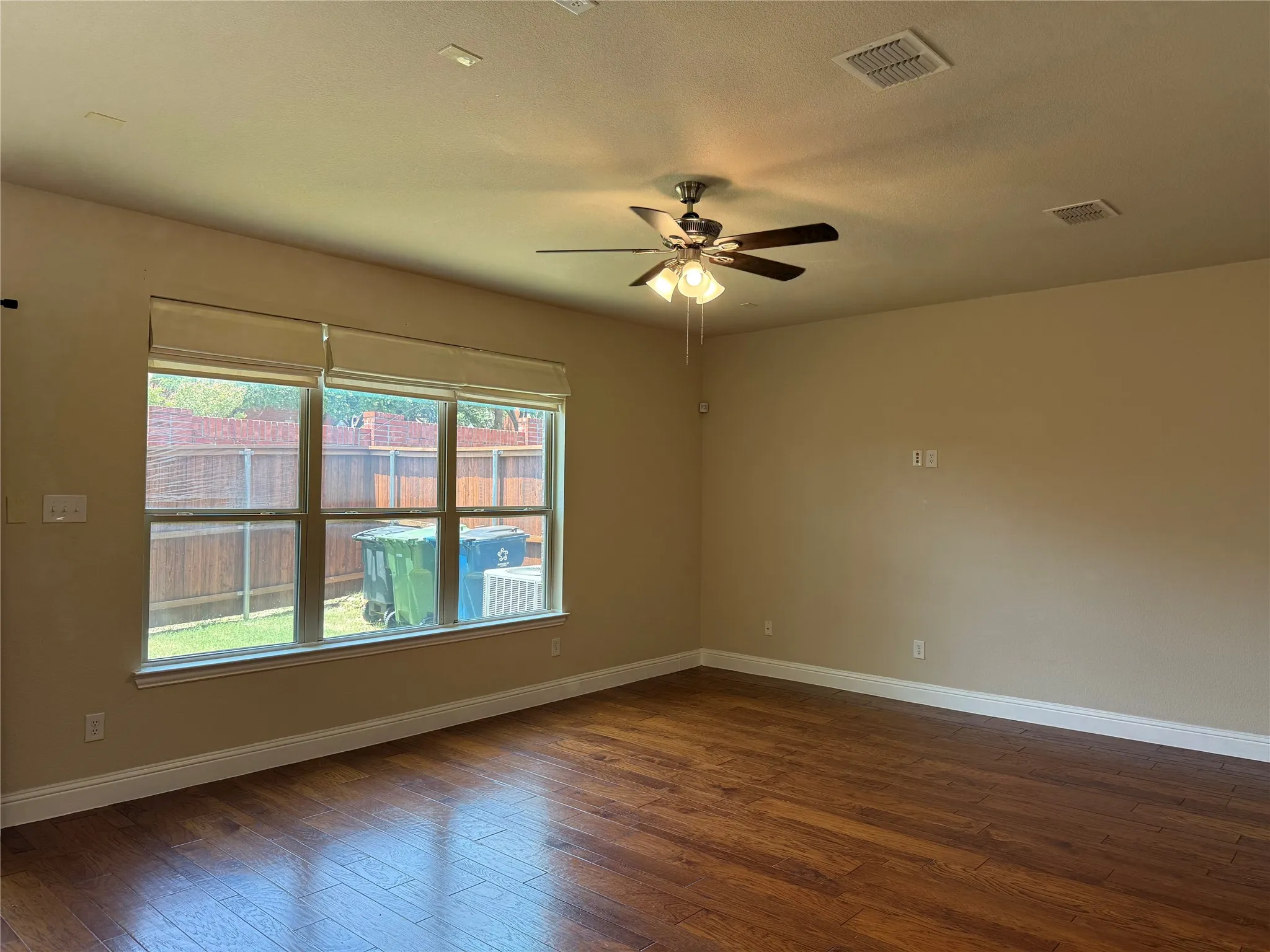 Hardwood-style flooring extends throughout this room, complemented by a multi-pane window with roller shades