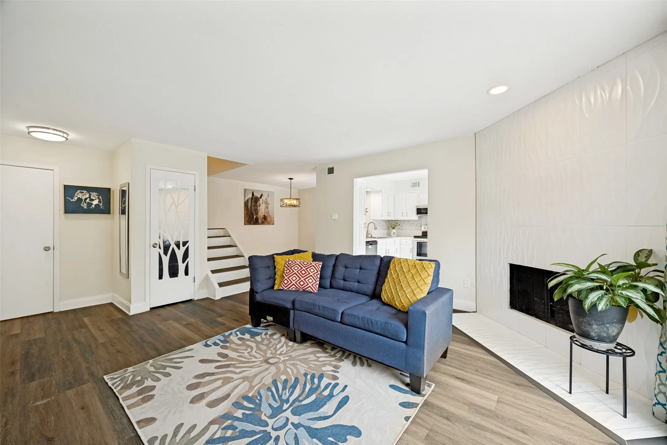 Living area featuring wood-finish flooring and a white fireplace with a textured surround
