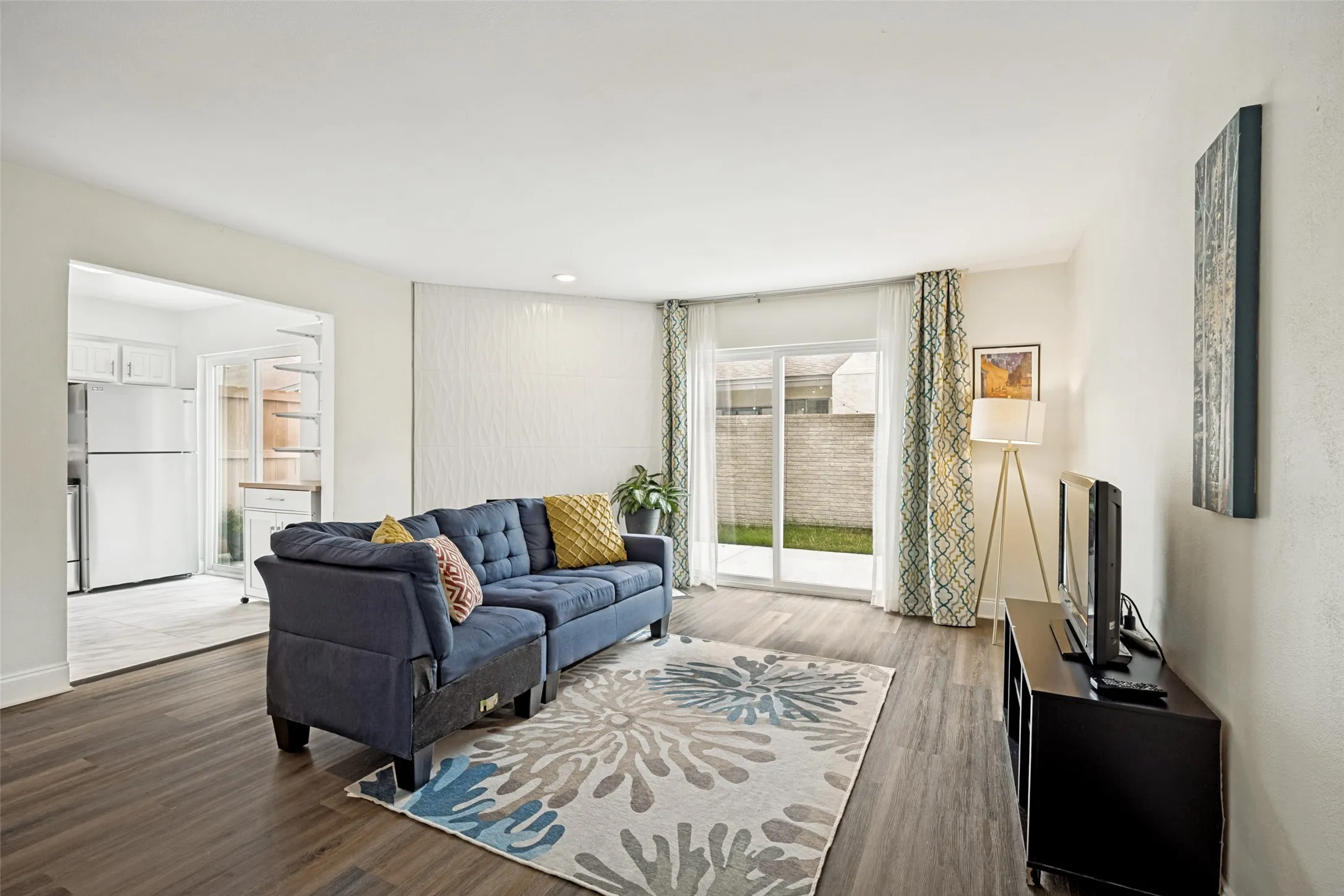Living area featuring wood-finish flooring, recessed lighting, and a white textured accent wall