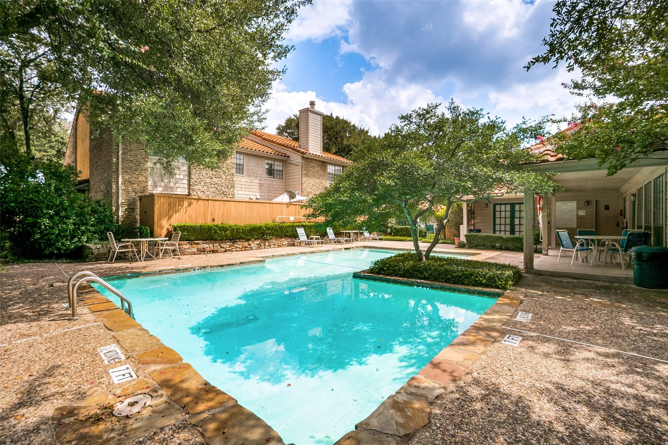 Resort-style pool with integrated landscape island, stone coping, and textured concrete decking