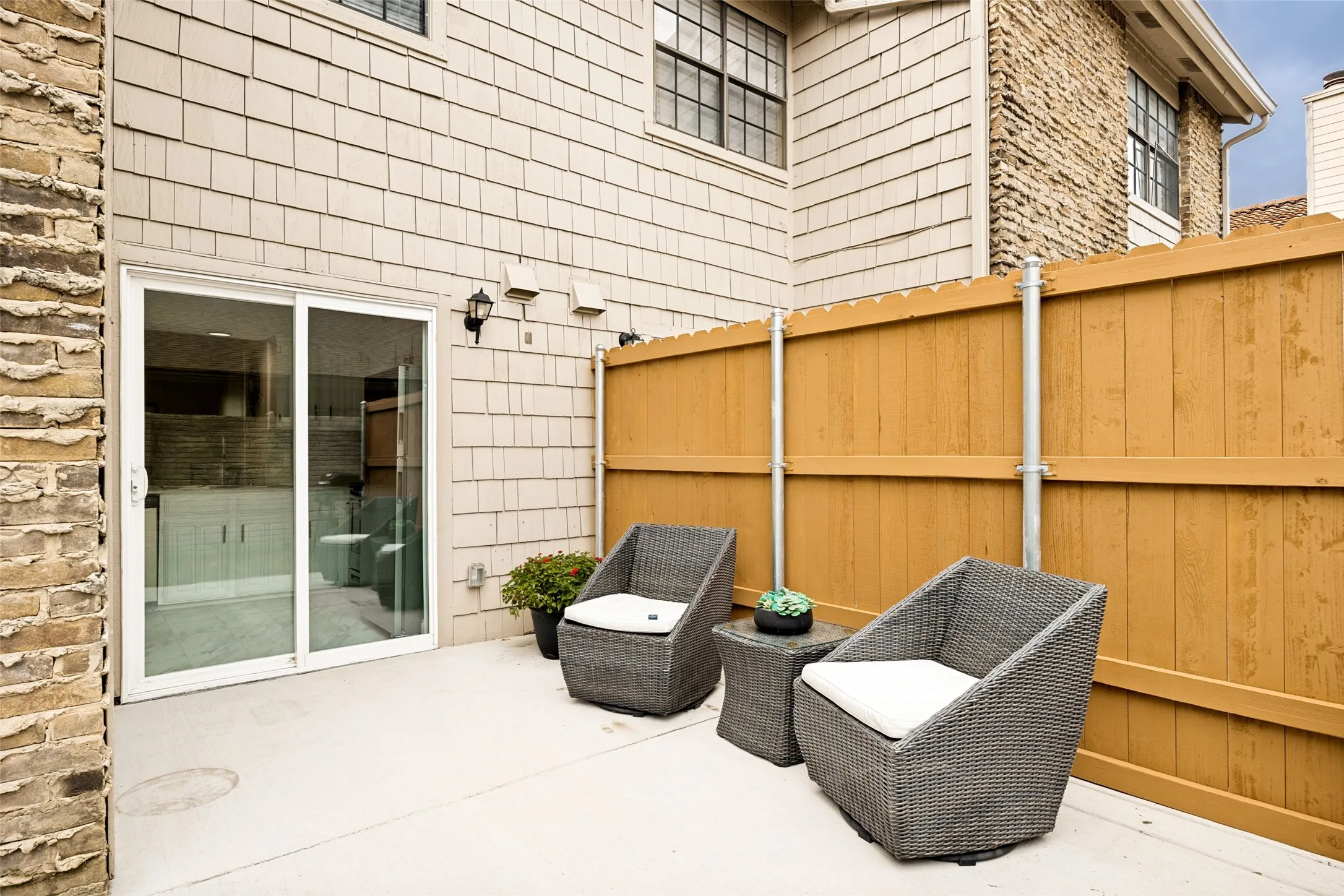 Private patio area with concrete flooring, wood privacy fence, and brick exterior accents