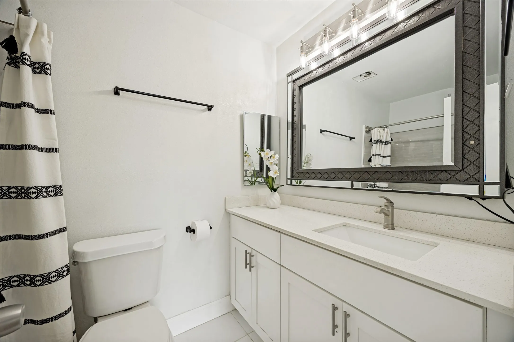 Bathroom vanity featuring a light-toned countertop, undermount sink, and brushed nickel faucet