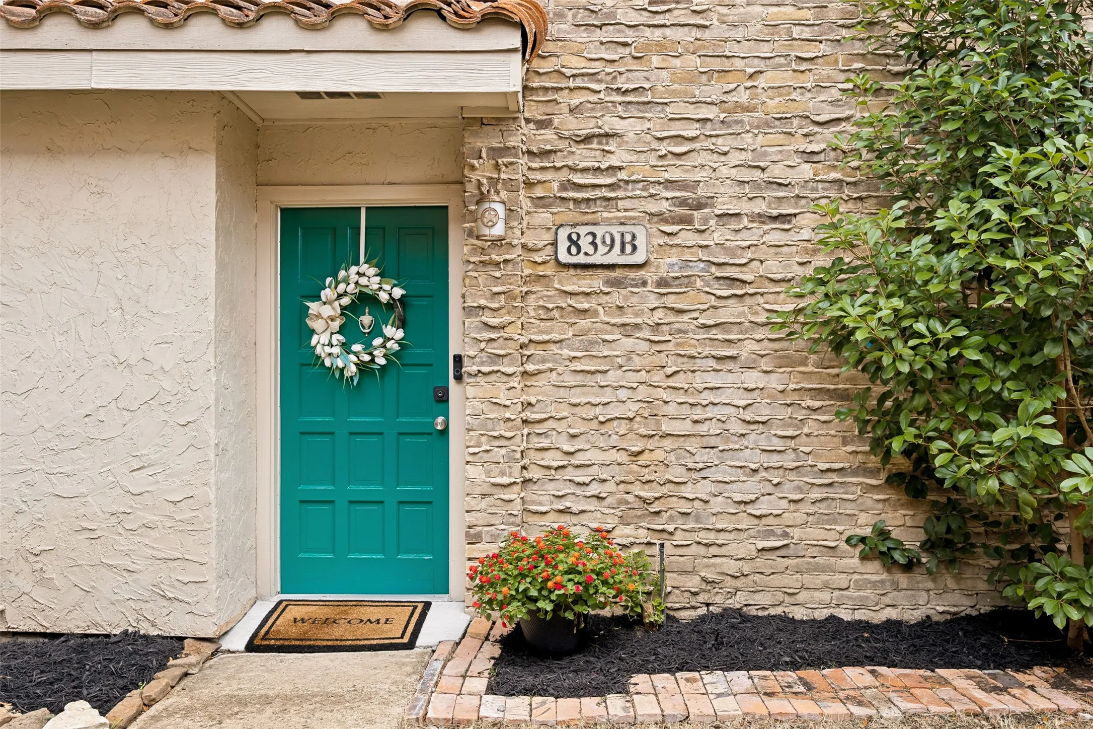 Vibrant teal front door with paneled detailing, complemented by textured stucco and stacked stone siding