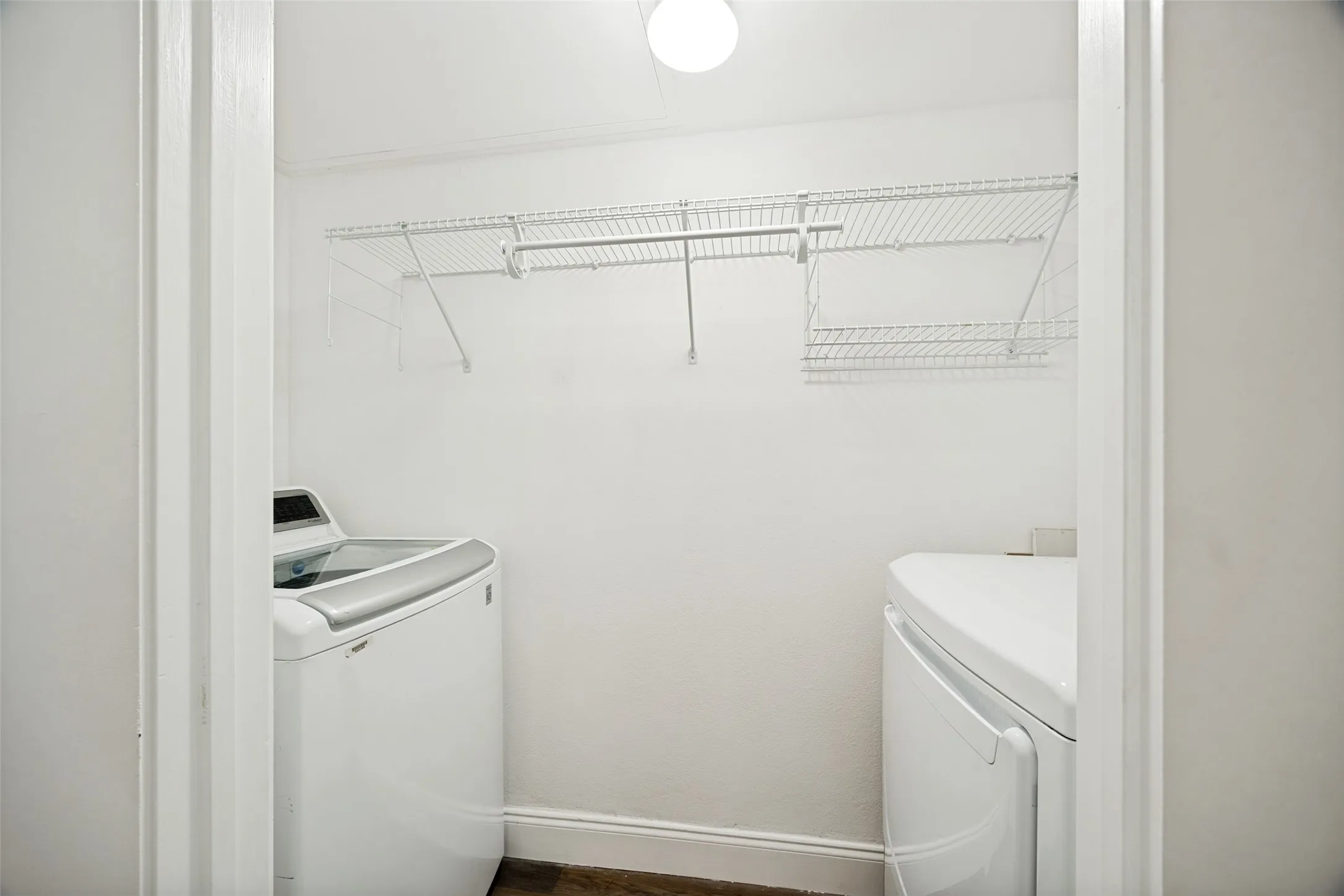 Dedicated utility area featuring a top-load washing machine, front-load dryer, and overhead wire shelving for storage