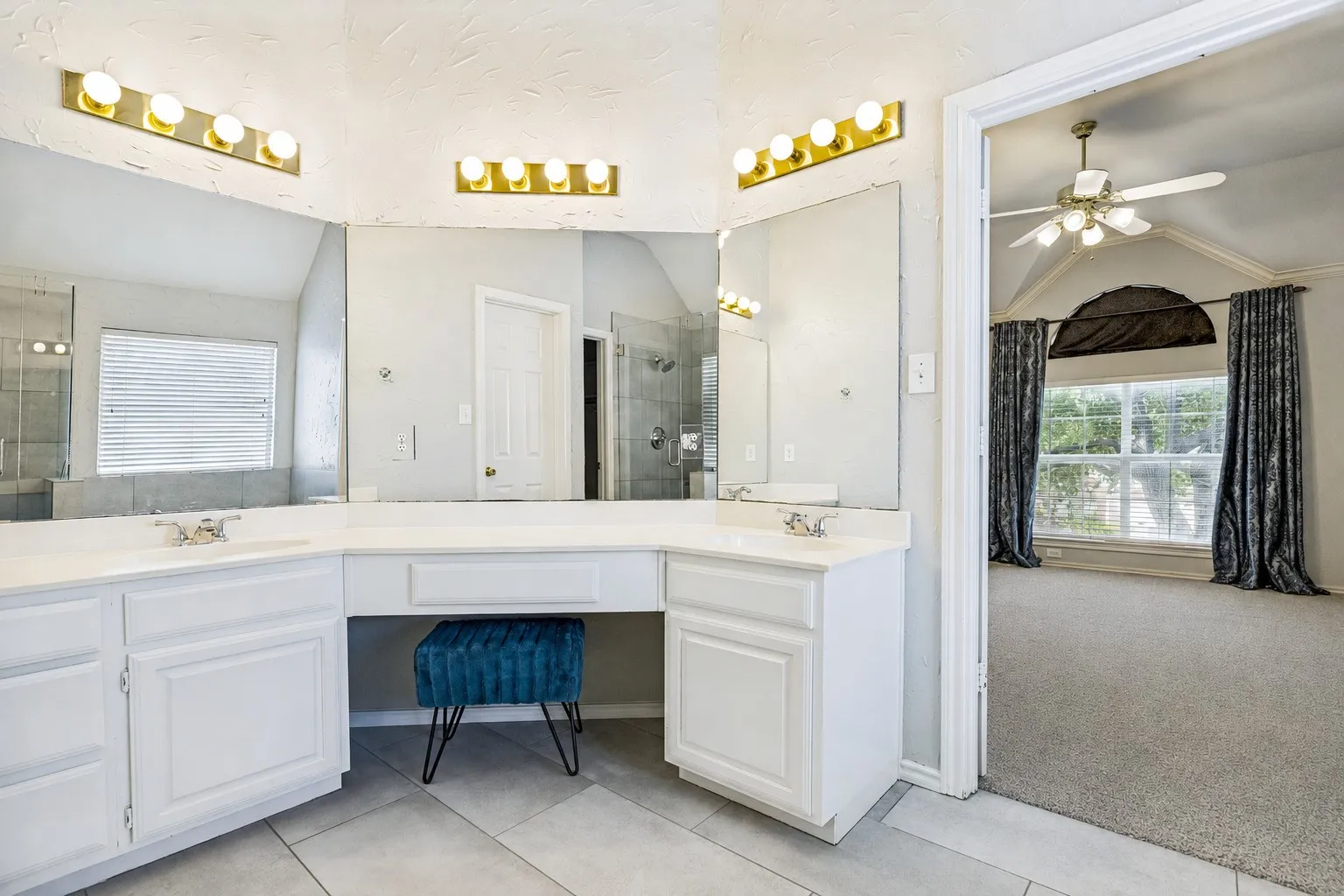 Double vanity with white cabinetry, integrated sinks, and contemporary gold-finish lighting fixtures