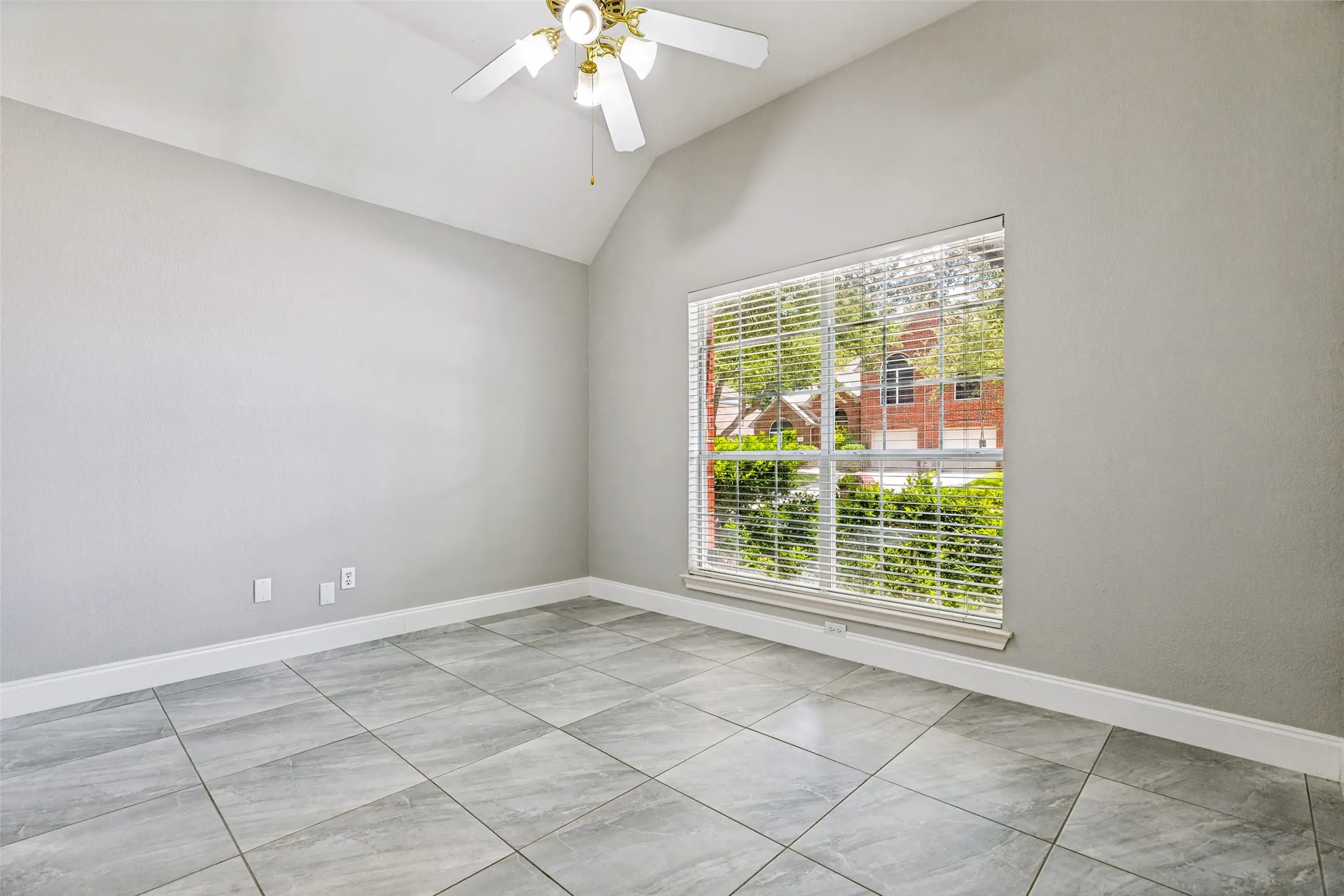 Interior room featuring light gray tile flooring, a large window with horizontal blinds, and a white ceiling fan with a light kit