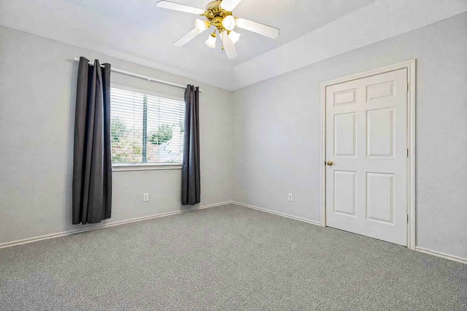 Carpeted room featuring a ceiling fan, a window with horizontal blinds, a paneled interior door, and light gray wall finishes