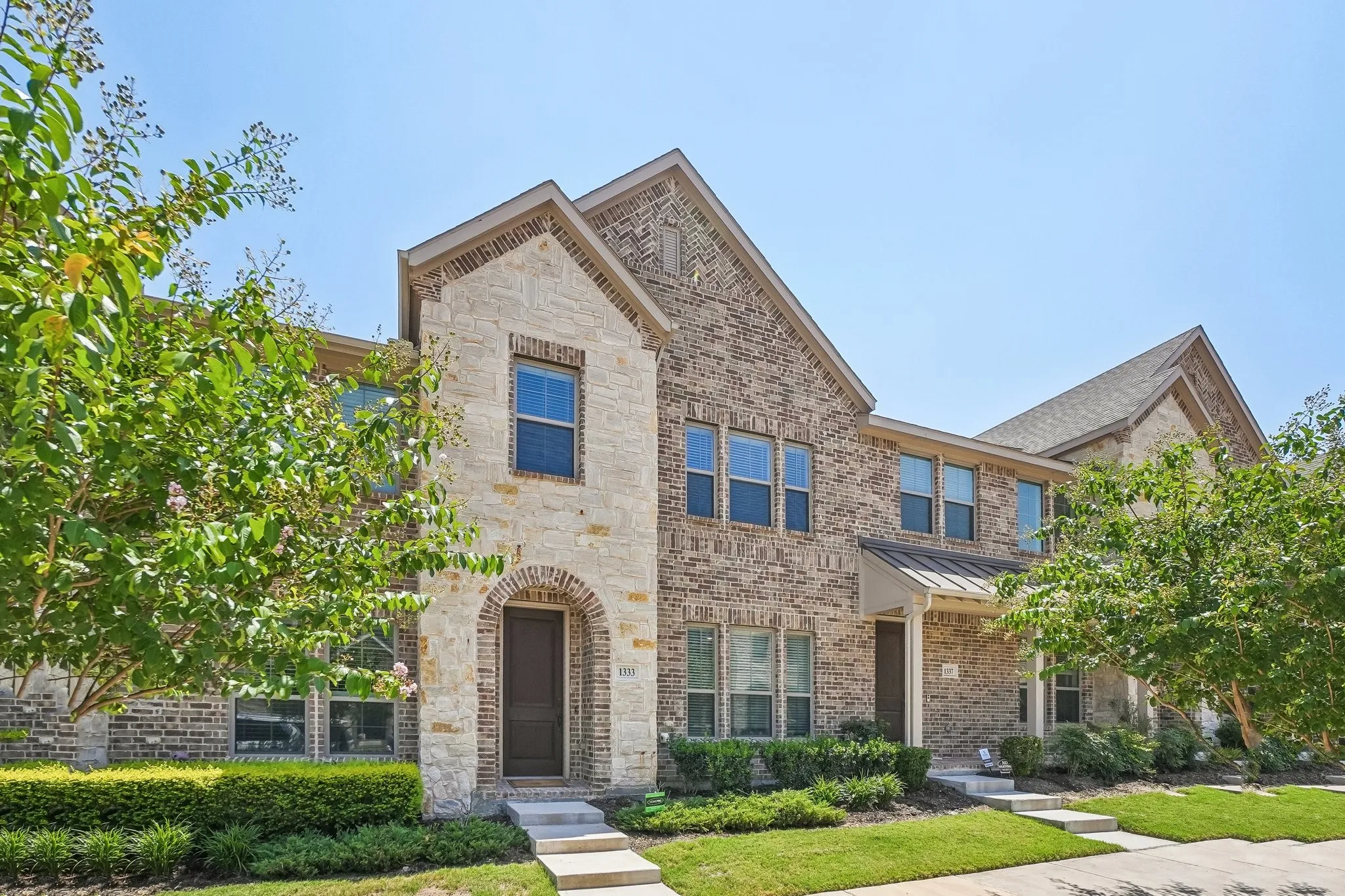 Two-story exterior featuring a prominent stone facade with brick accents and multiple windows