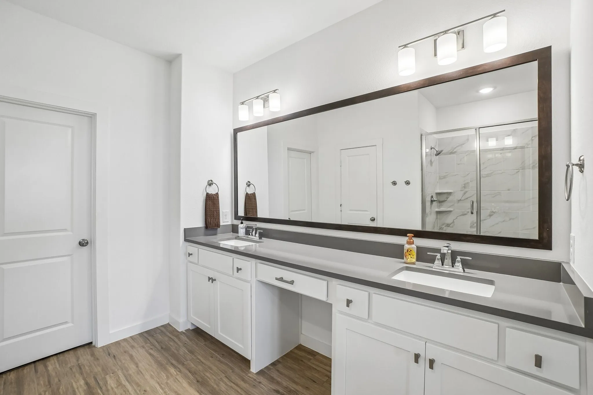 Bathroom featuring dual vanity with undermount sinks, stone countertops, and extensive framed mirror