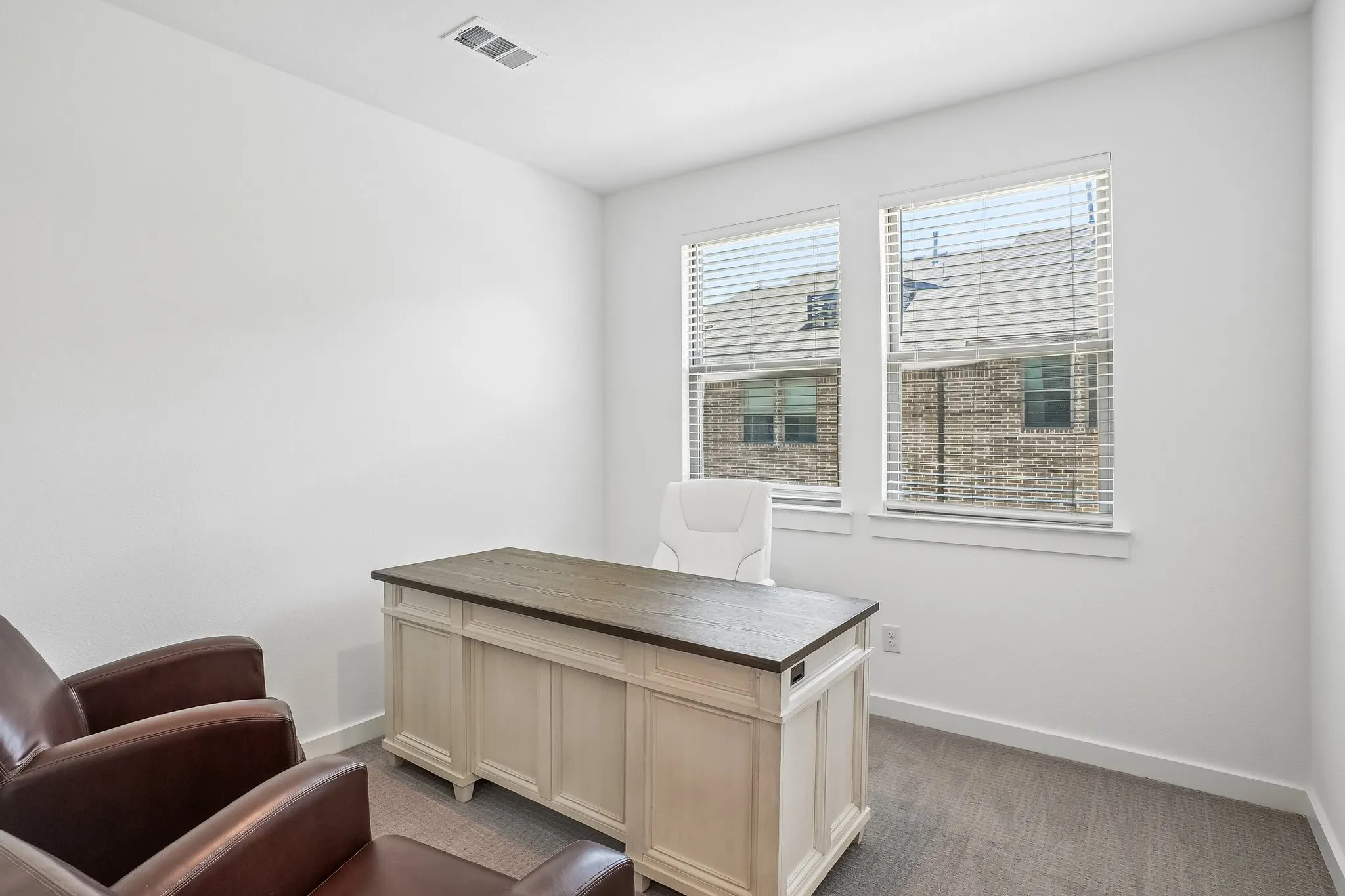 Room featuring two windows with horizontal blinds and neutral carpeting