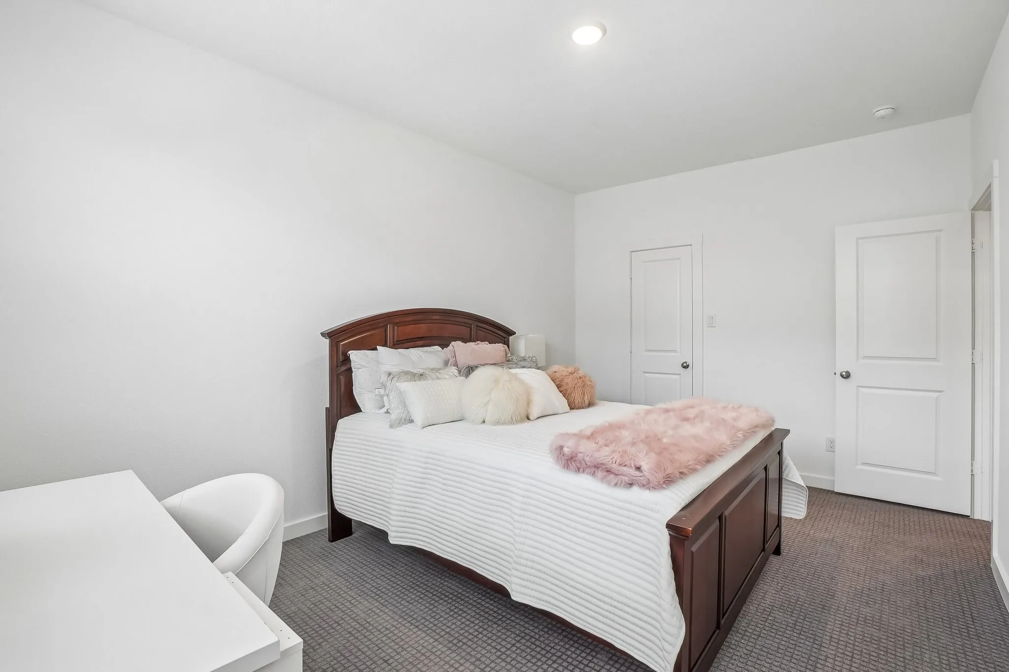 Bedroom featuring bright white walls, recessed ceiling lighting, two white panel doors, and gray carpeting
