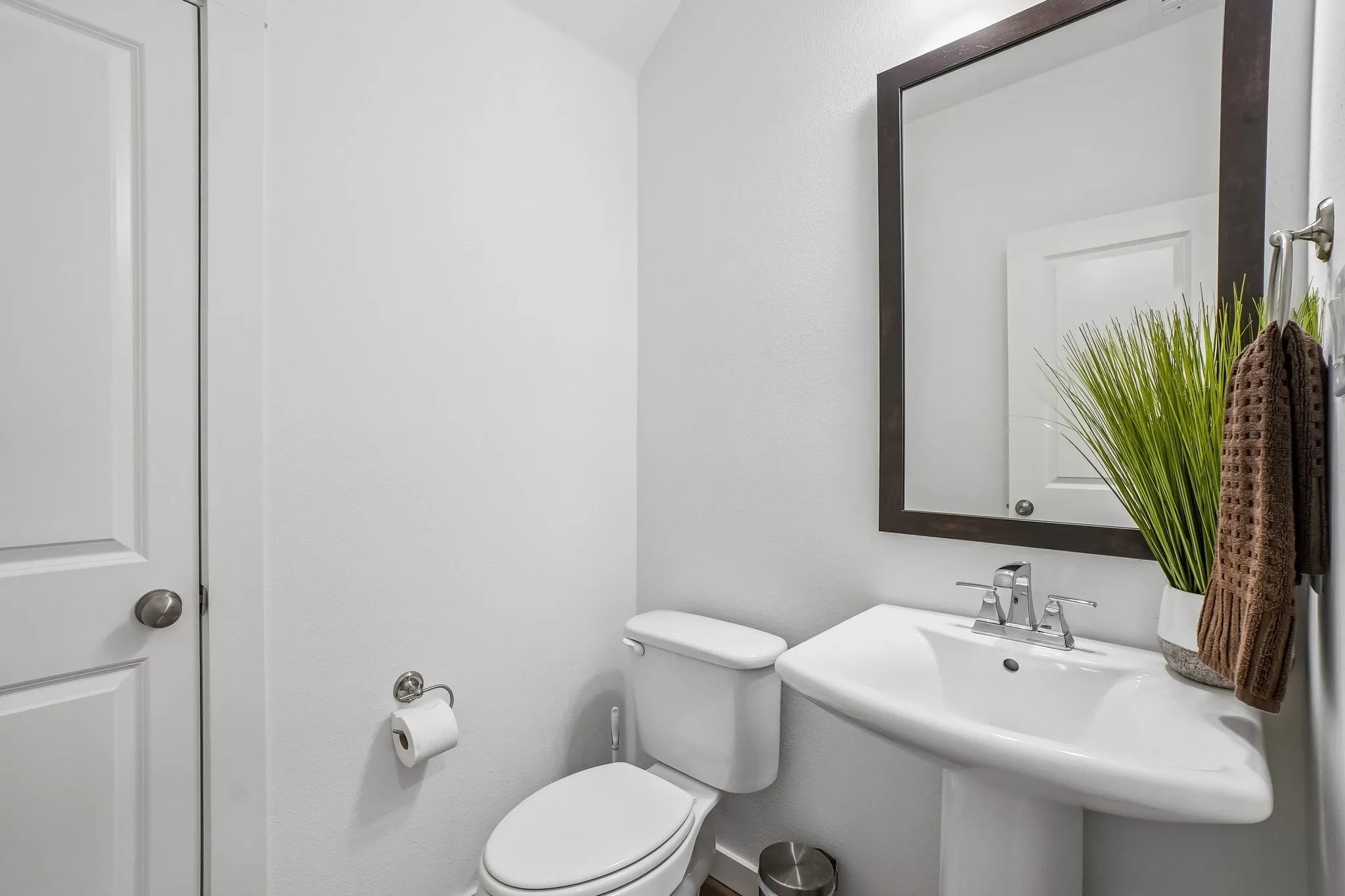 Pedestal sink with chrome fixtures and a framed mirror