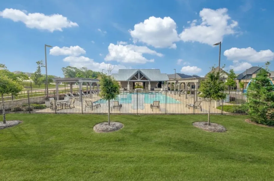 Community pool area featuring a covered pavilion with a gabled metal roof, multiple lounge chairs, and a shaded pergola