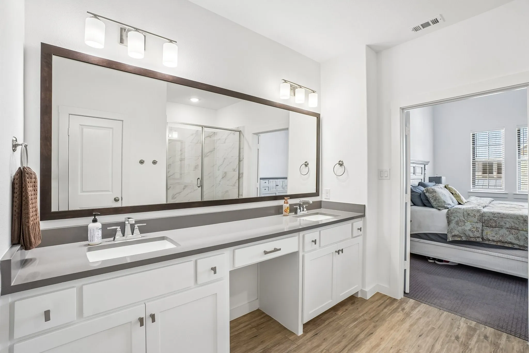Double vanity with gray countertops, under-mount sinks, and white cabinetry