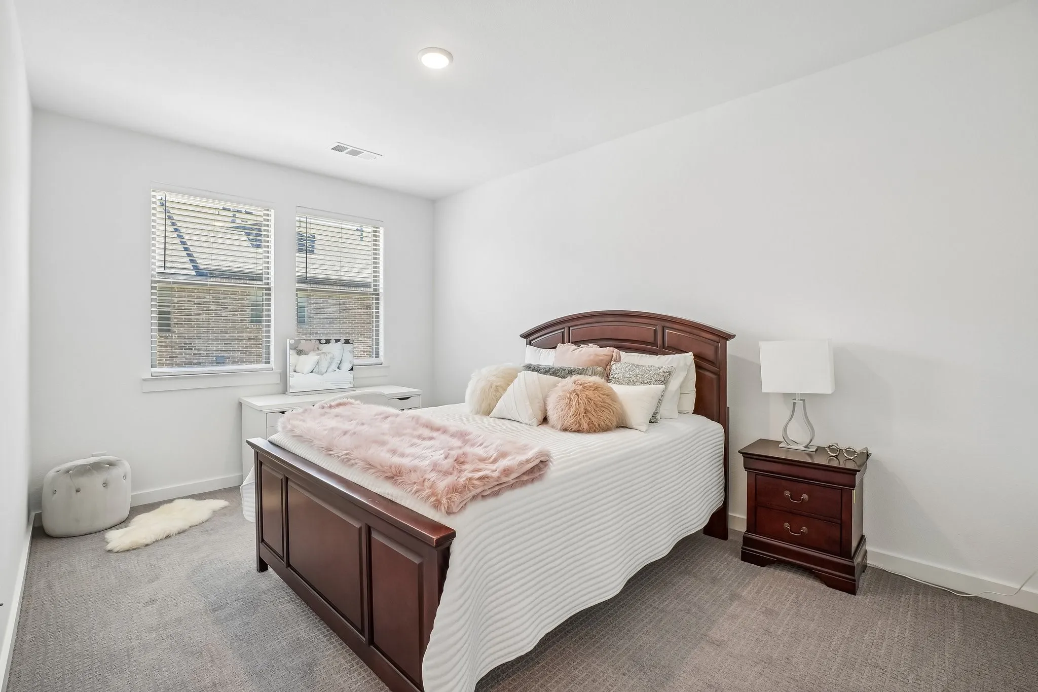 Bright interior space featuring a recessed ceiling light, two windows with blinds, light gray patterned carpet, white walls, and white baseboards