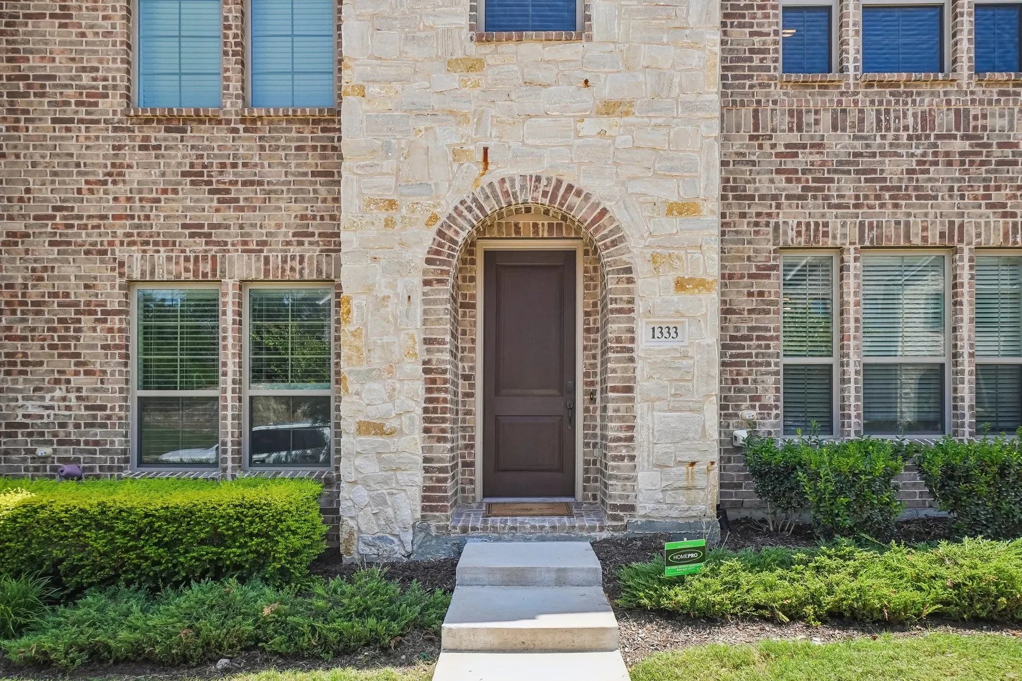 Arched stone entryway featuring a dark wood door with house number 1333