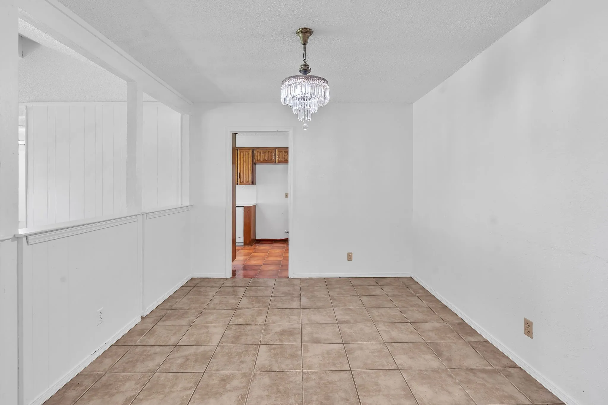 Recessed chandelier lighting over neutral-toned tile flooring