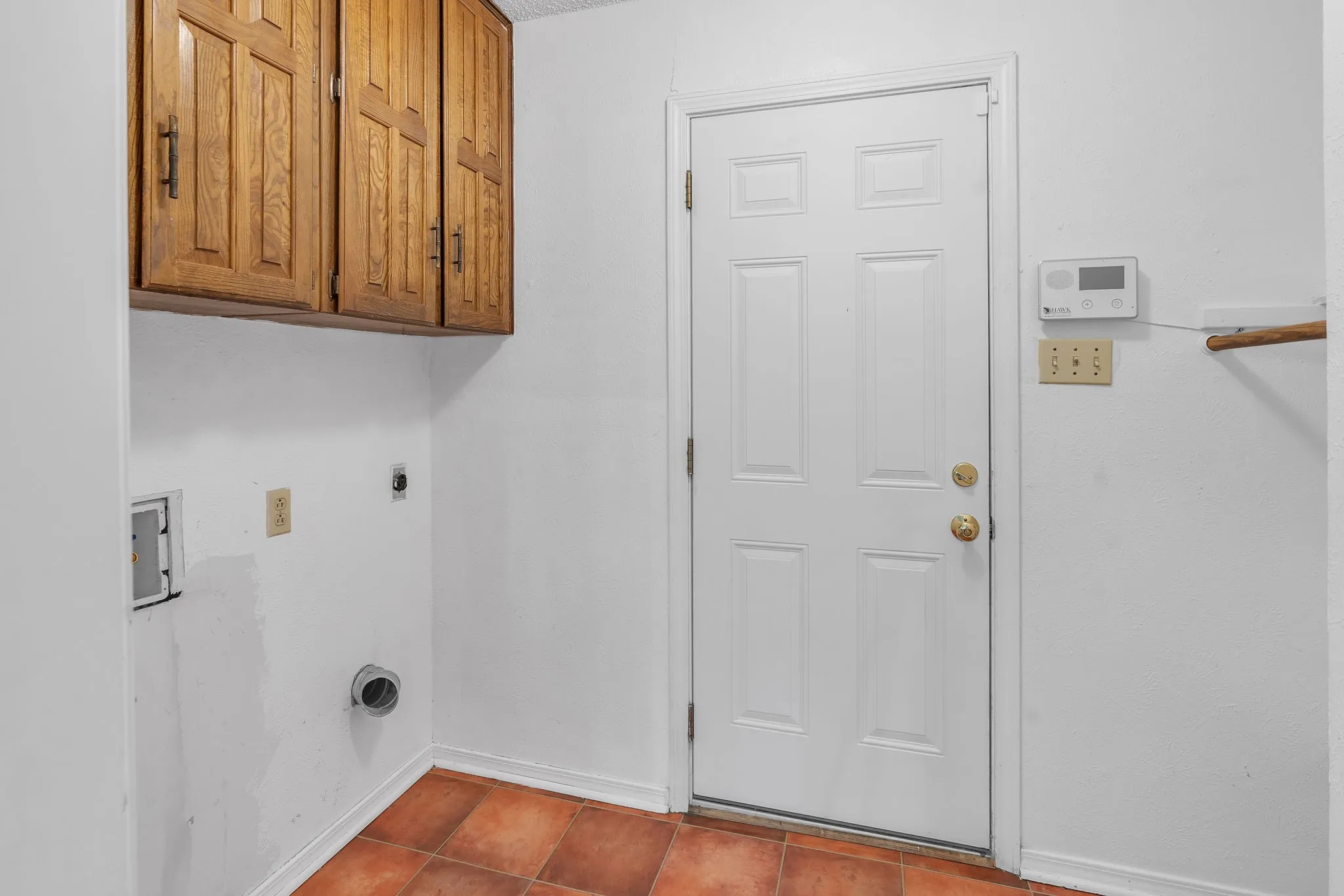 Laundry area featuring wood-finish cabinetry, tile flooring, and a paneled entry door
