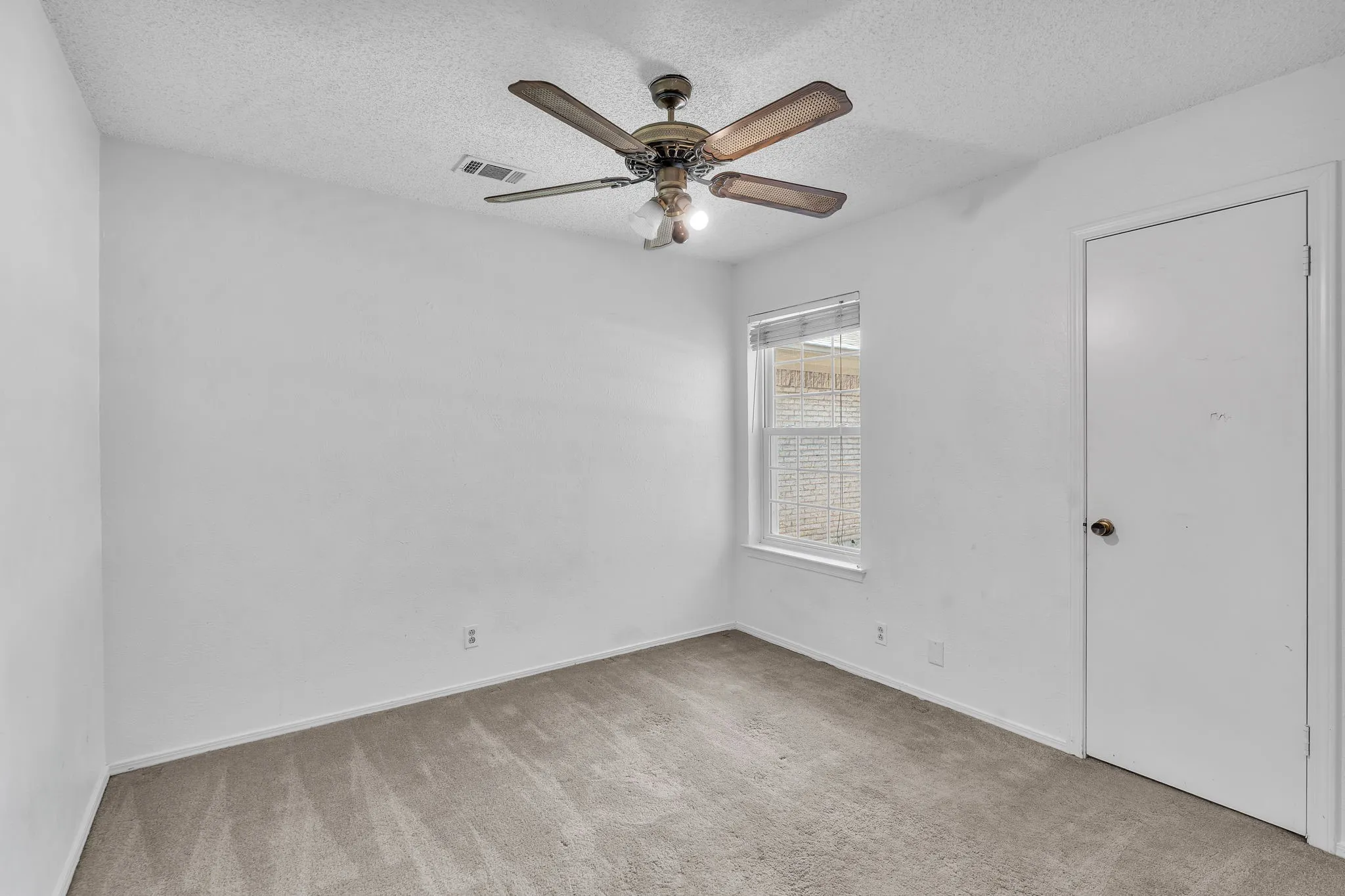 Carpeted room featuring a ceiling fan with integrated lighting, a single window, and a white interior door