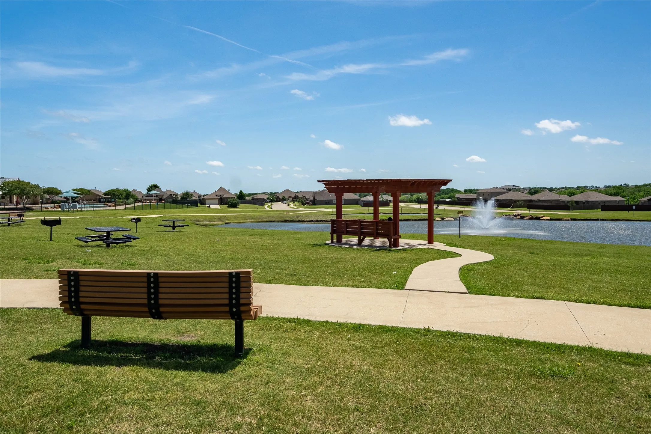 View of property's community with a water view, a pergola, and a lawn