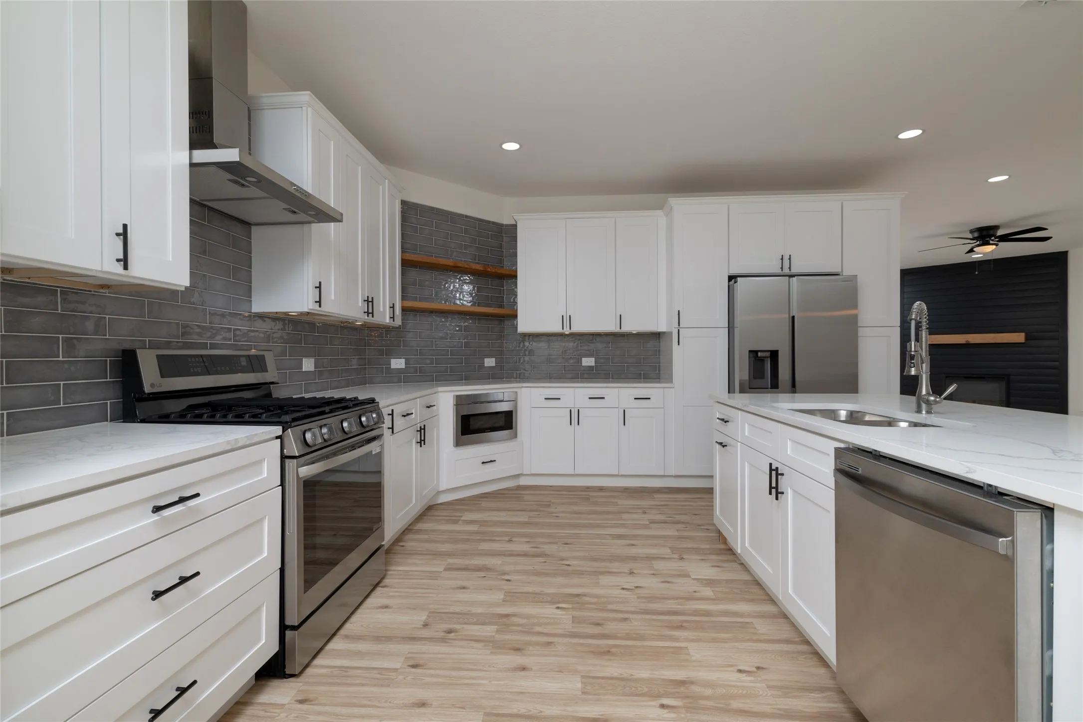 Modern kitchen featuring white shaker cabinetry, stainless steel appliances, a subway tile backsplash, light wood-finish flooring, and recessed lighting