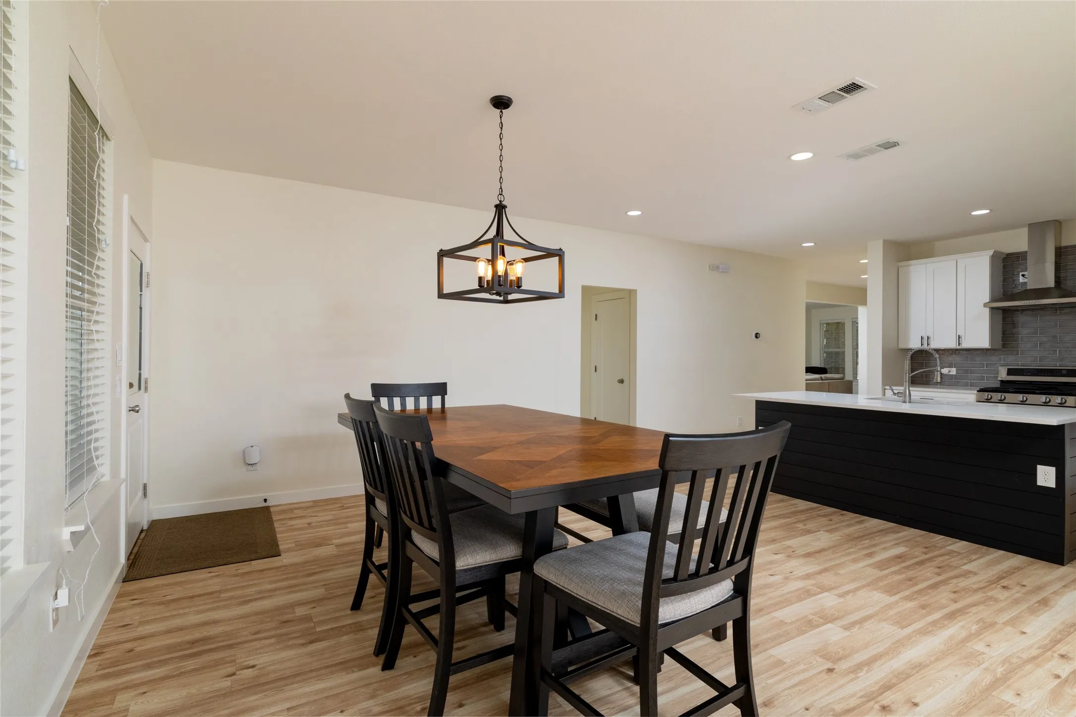 Open-concept dining area with wood-finish flooring, featuring a contemporary chandelier