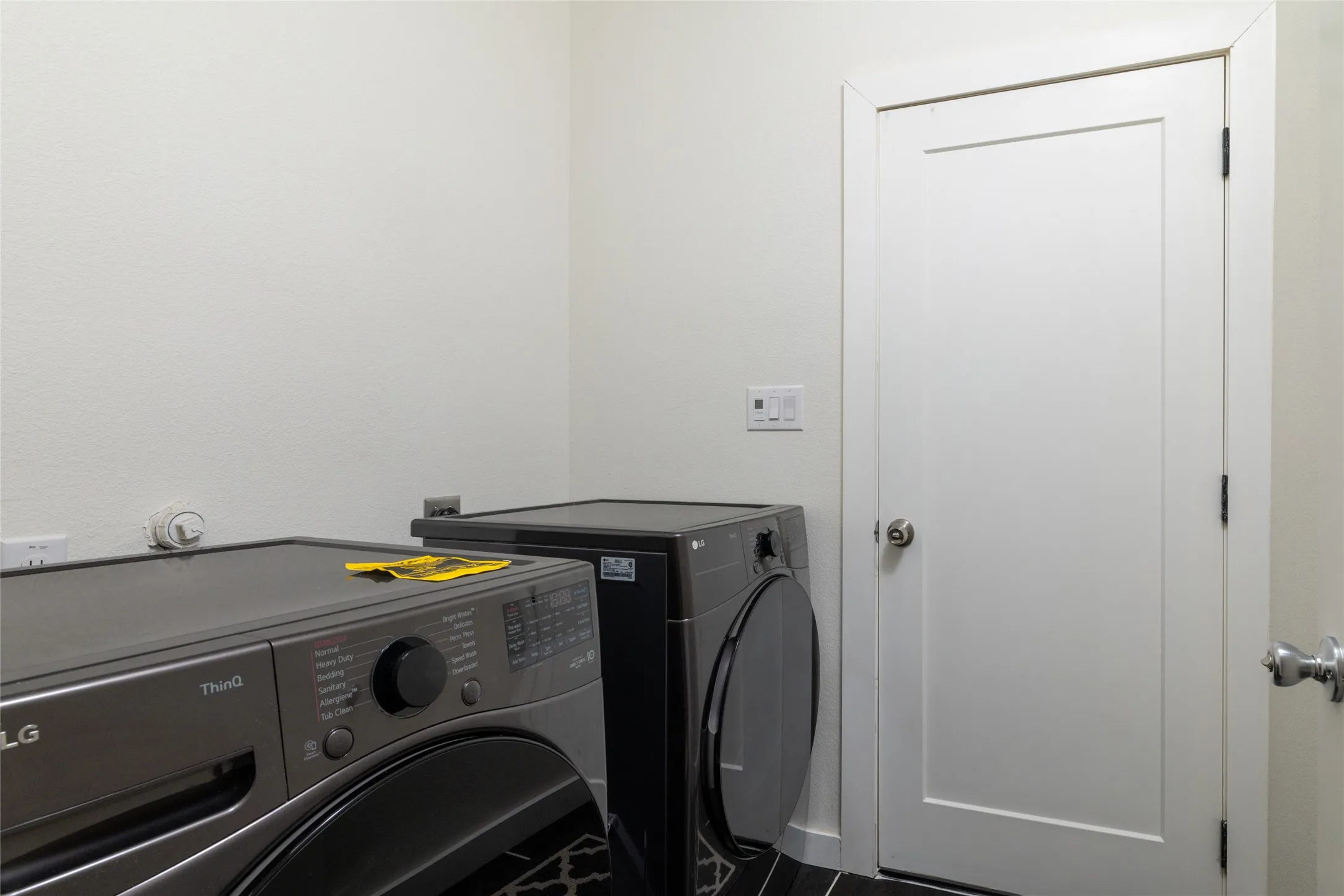 Dedicated laundry area featuring a white shaker-style door, light wall paint, and dark patterned flooring