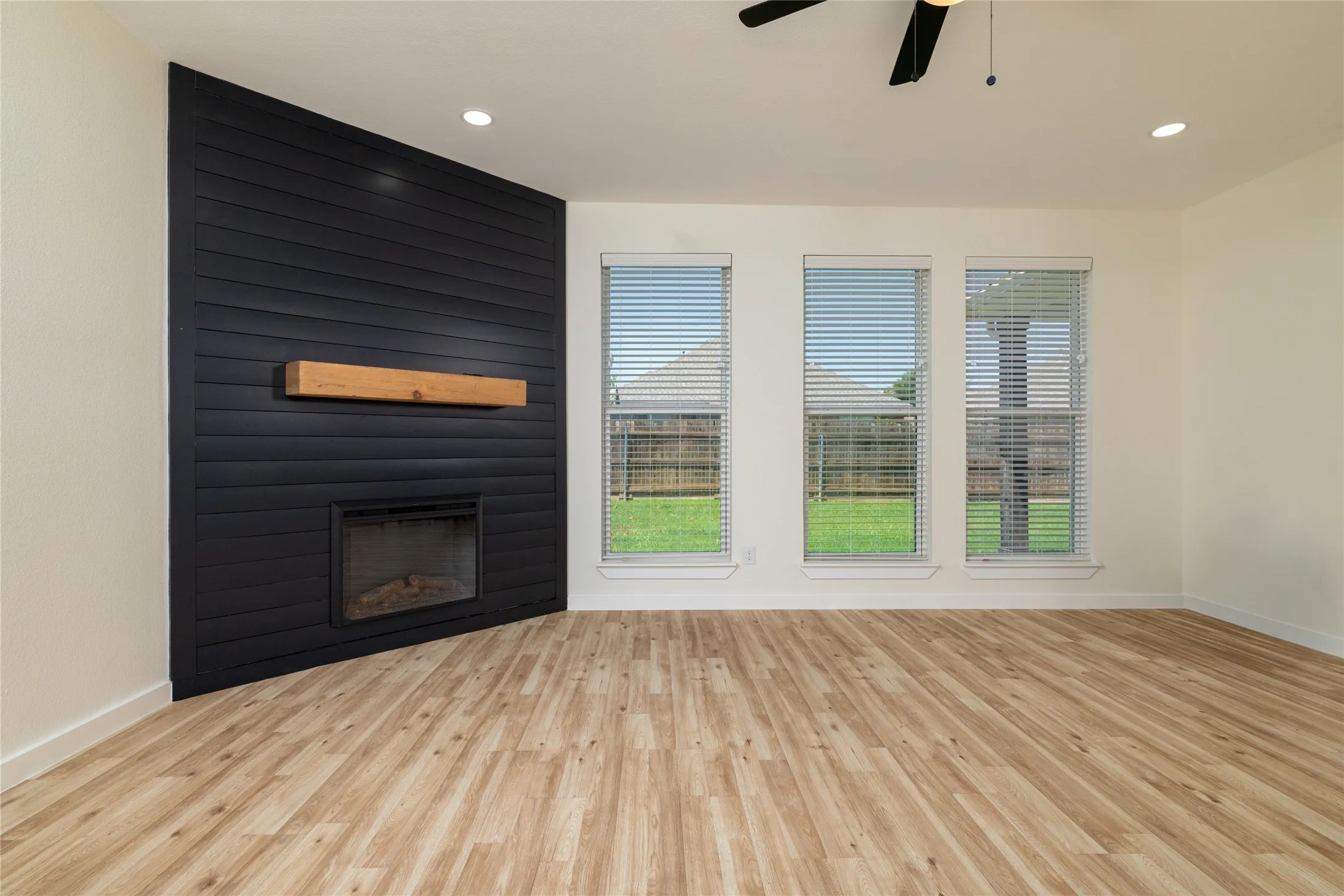 Original Photo of last 2 AI Photos - Living area featuring a dark shiplap accent wall with an integrated fireplace and natural wood mantel