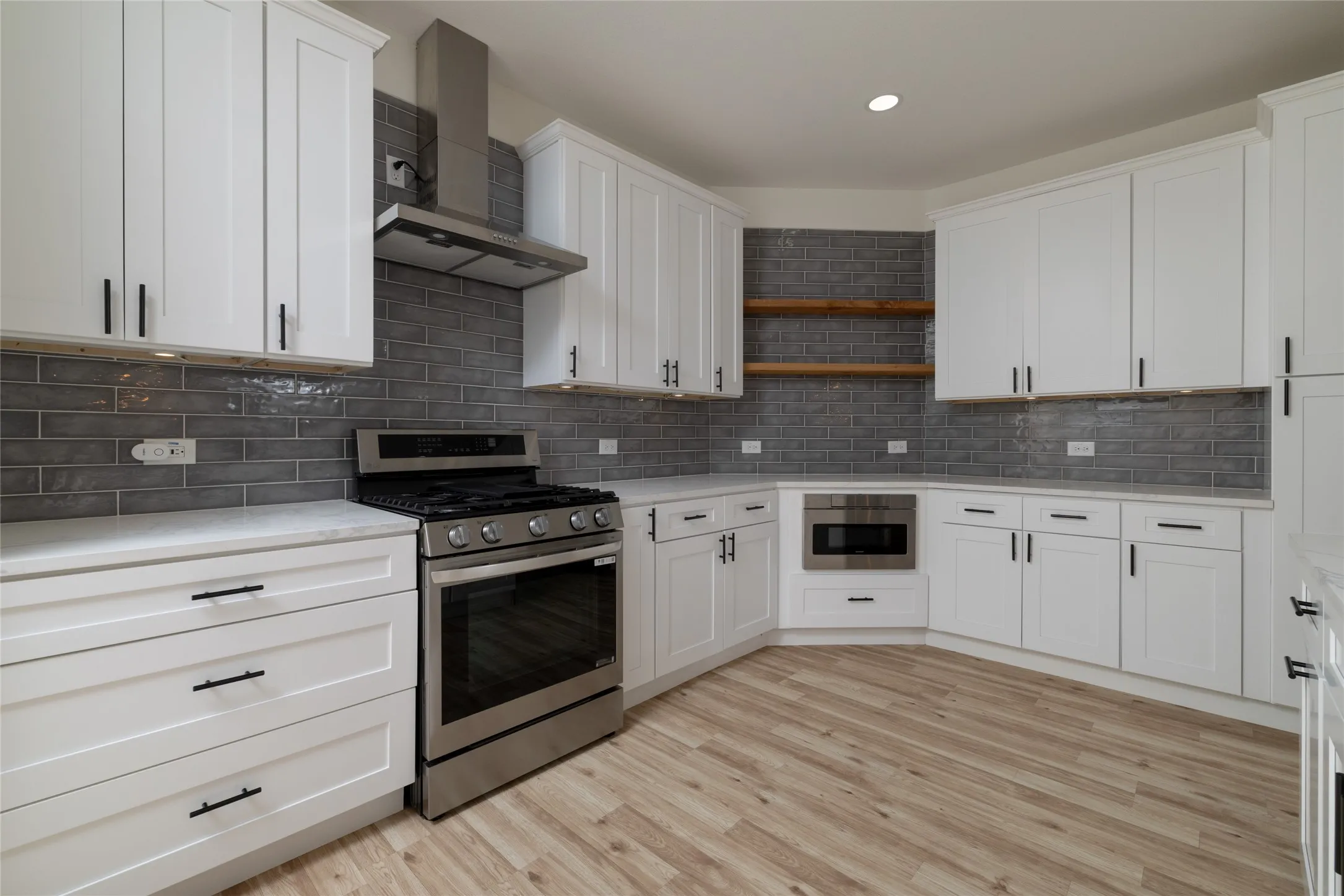 Original of AI Modern kitchen featuring white shaker cabinetry, stainless steel appliances, a dark gray subway tile backsplash, light wood-finish flooring, and light-toned countertops