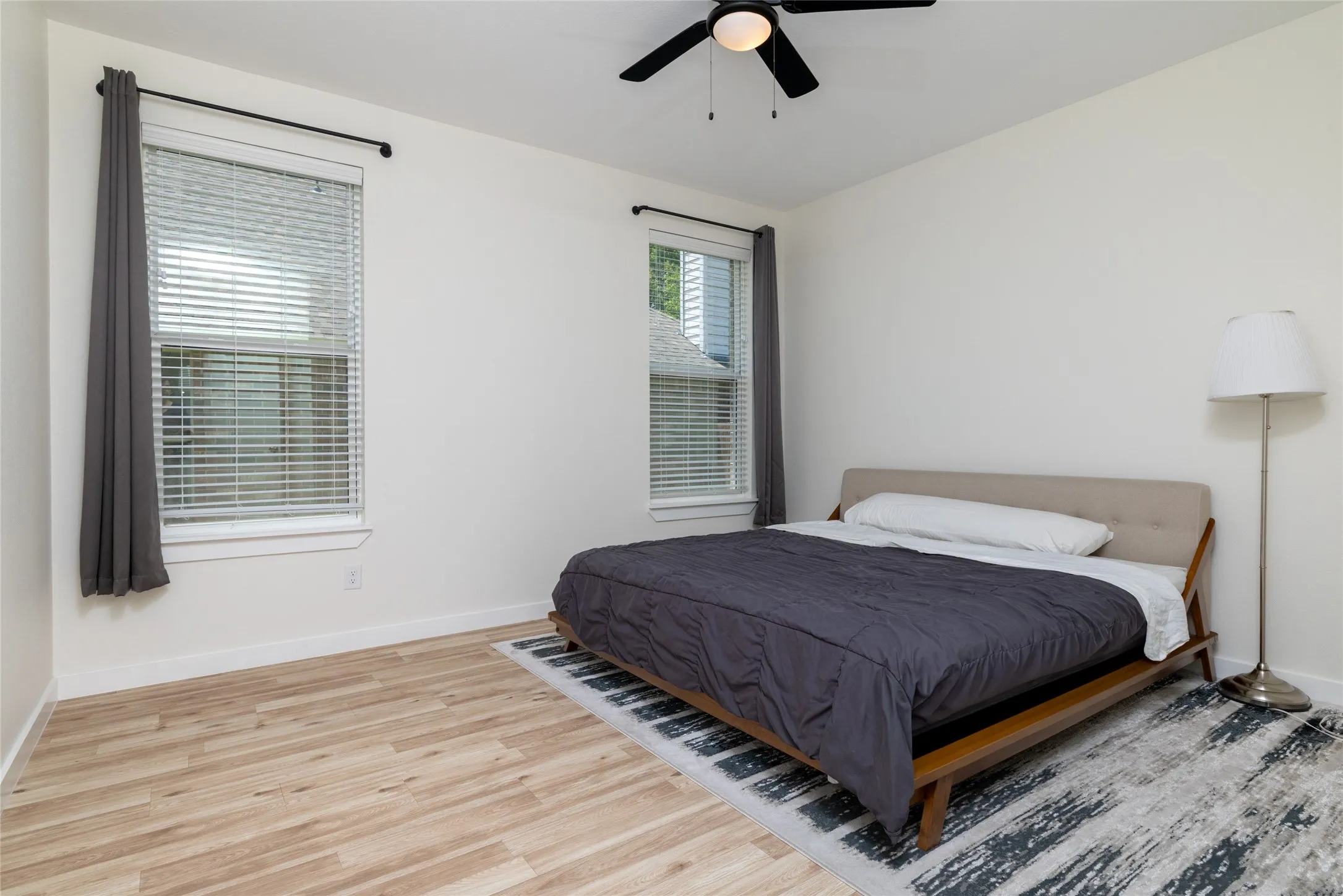 2nd of the 2 back bedrooms - Bright room with light wood-finish flooring, white walls, and a black ceiling fan
