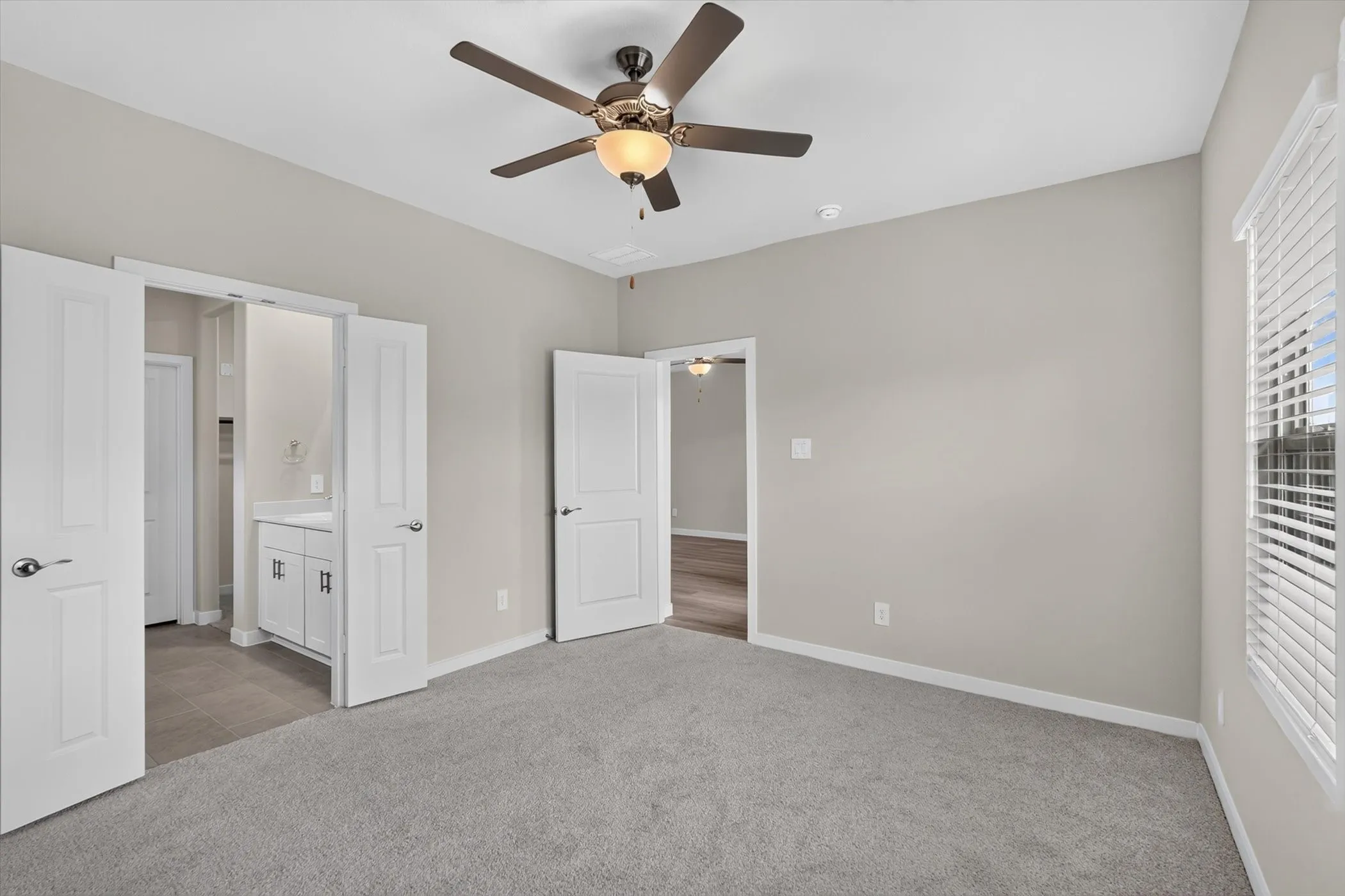 Carpeted room with light gray walls, a ceiling fan with integrated lighting, and a window with white blinds