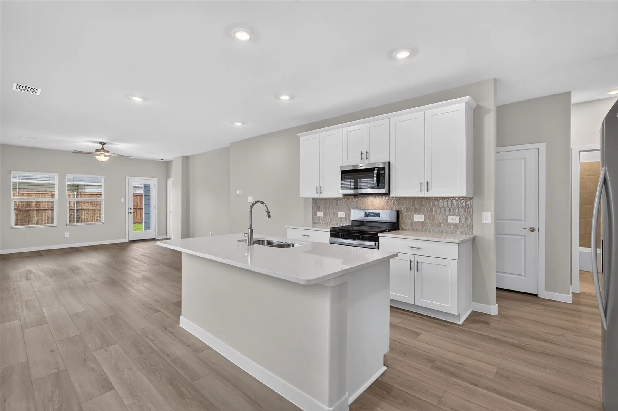 Kitchen featuring white cabinetry with brushed nickel hardware, a stainless steel microwave, and a gas range