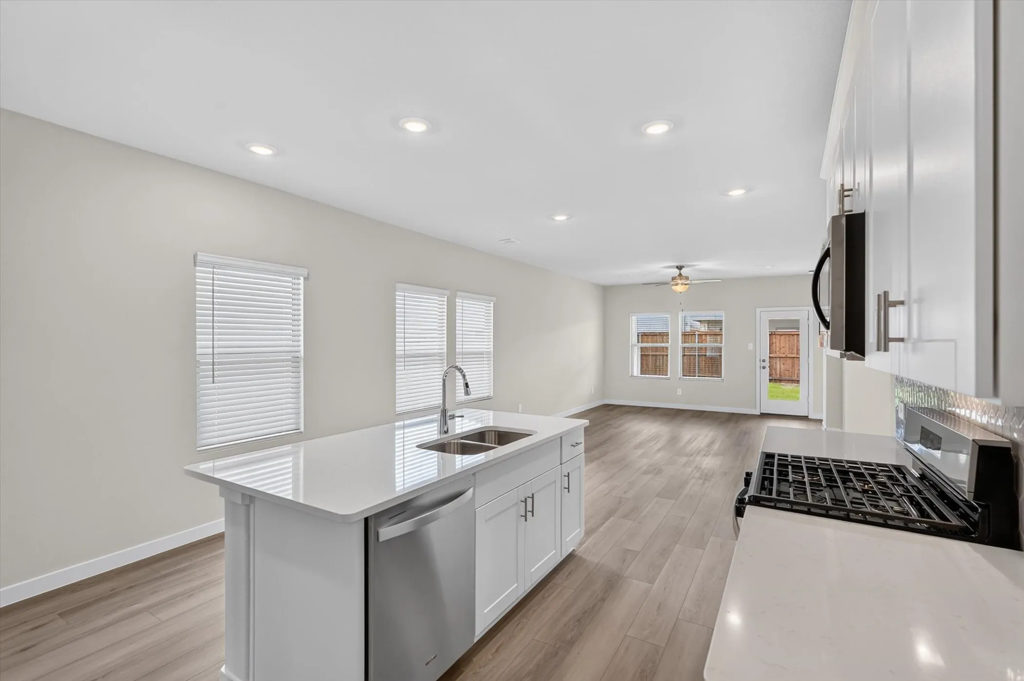 Modern kitchen island featuring a double stainless steel sink, a stainless steel dishwasher, and white cabinetry with brushed nickel hardware