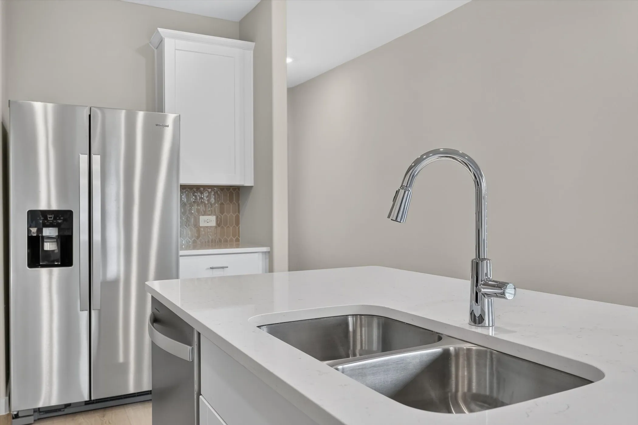 Stainless steel double basin sink with a chrome gooseneck faucet, set within a white countertop