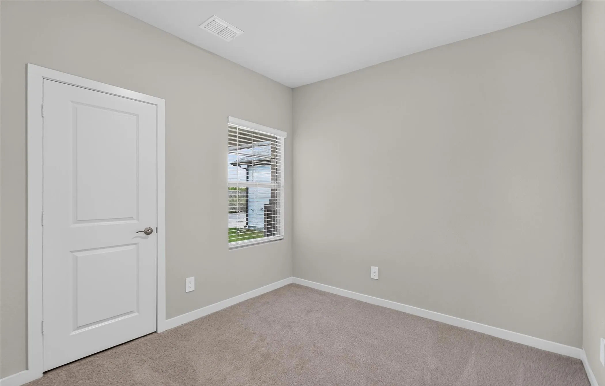 Neutral-toned interior room featuring light gray walls, white trim, and light brown carpeting
