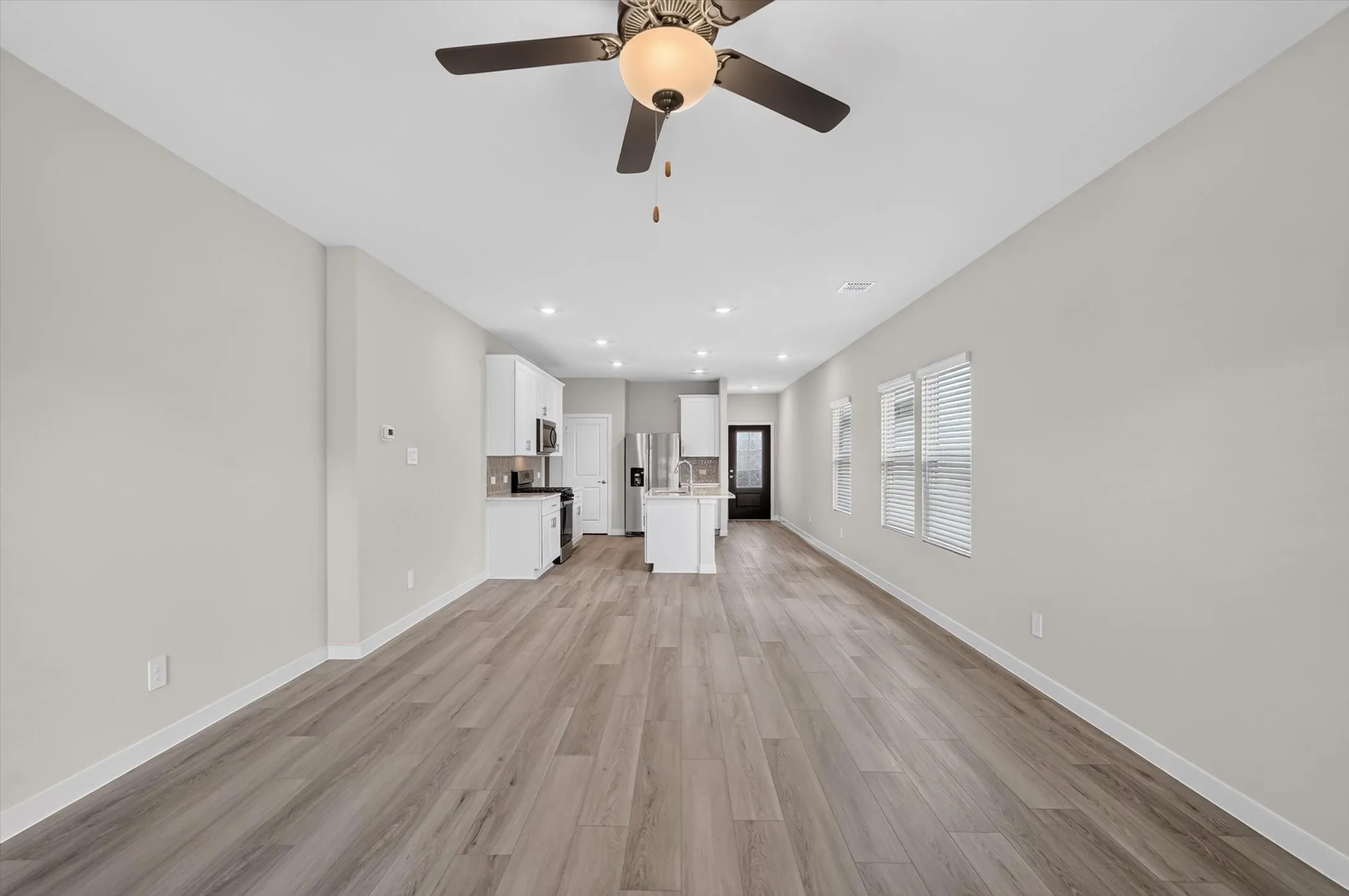 Expansive open-concept living space featuring wood-finish flooring, recessed lighting, and a ceiling fan