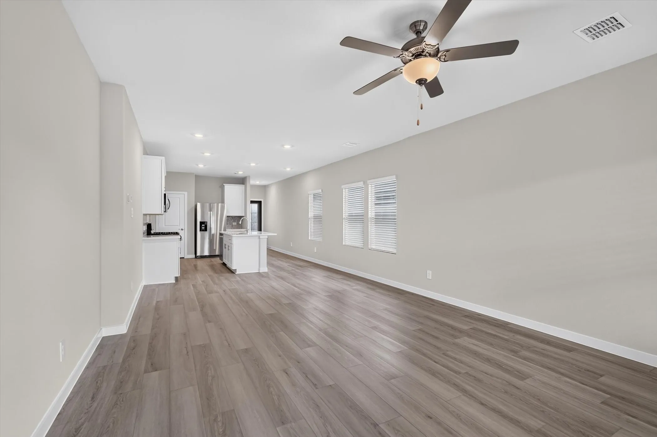 Open-concept living area featuring wood-finish flooring, recessed lighting, and a ceiling fan
