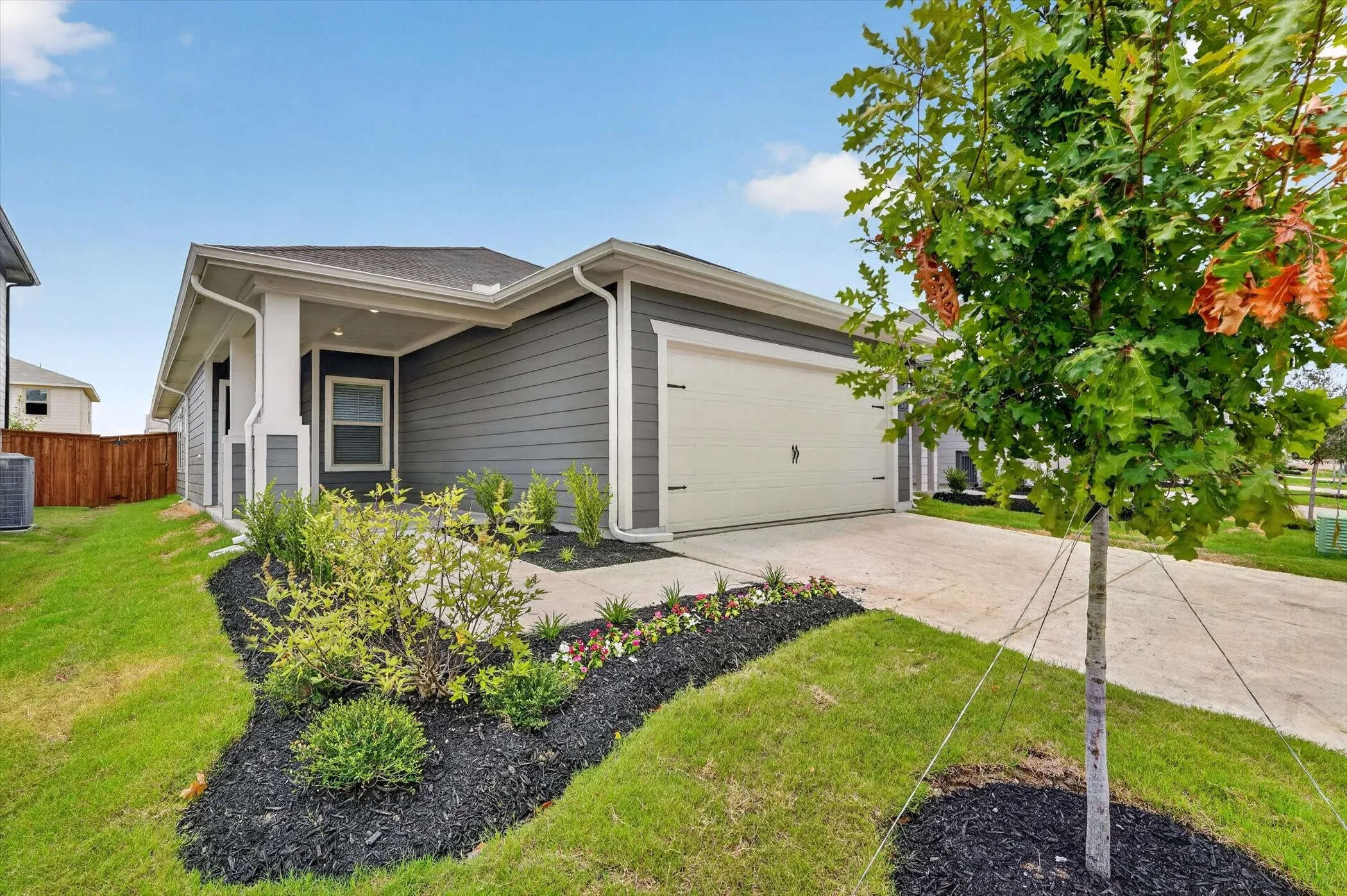Contemporary residence featuring grey siding, an attached garage, and a concrete driveway