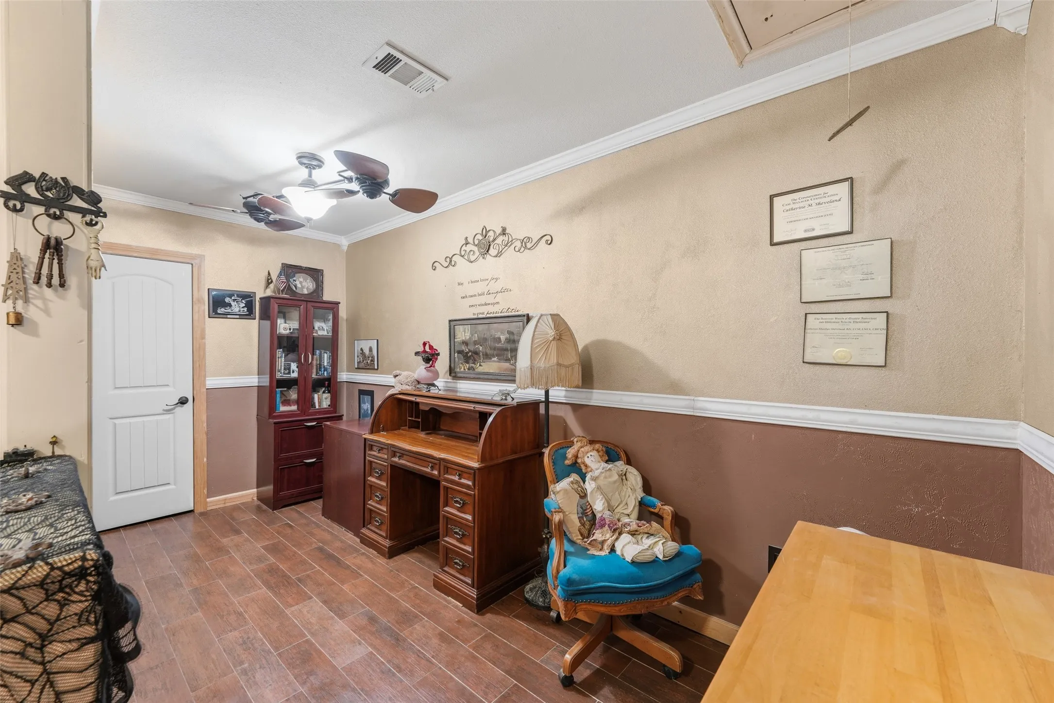 Room featuring wood-finish flooring, two-tone painted walls with chair rail molding, and crown molding