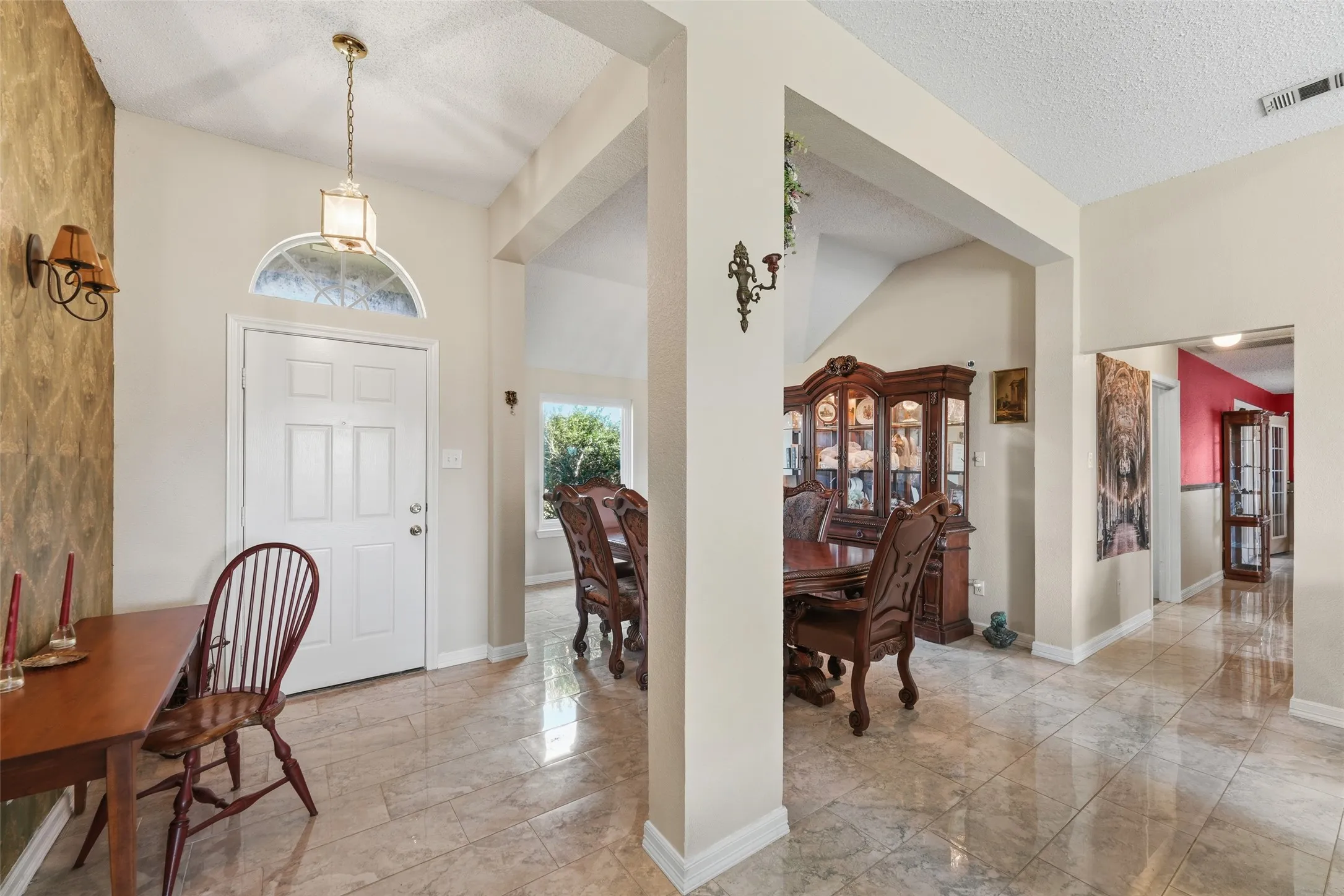 Entryway featuring a white paneled door with an arched transom window, a brass-finish pendant light, and tile flooring