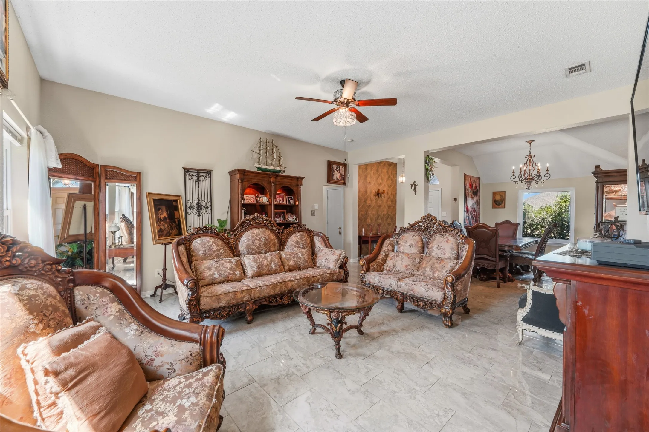 Living area featuring light-toned tile flooring, a ceiling fan with integrated lighting, and an arched entryway to the dining area