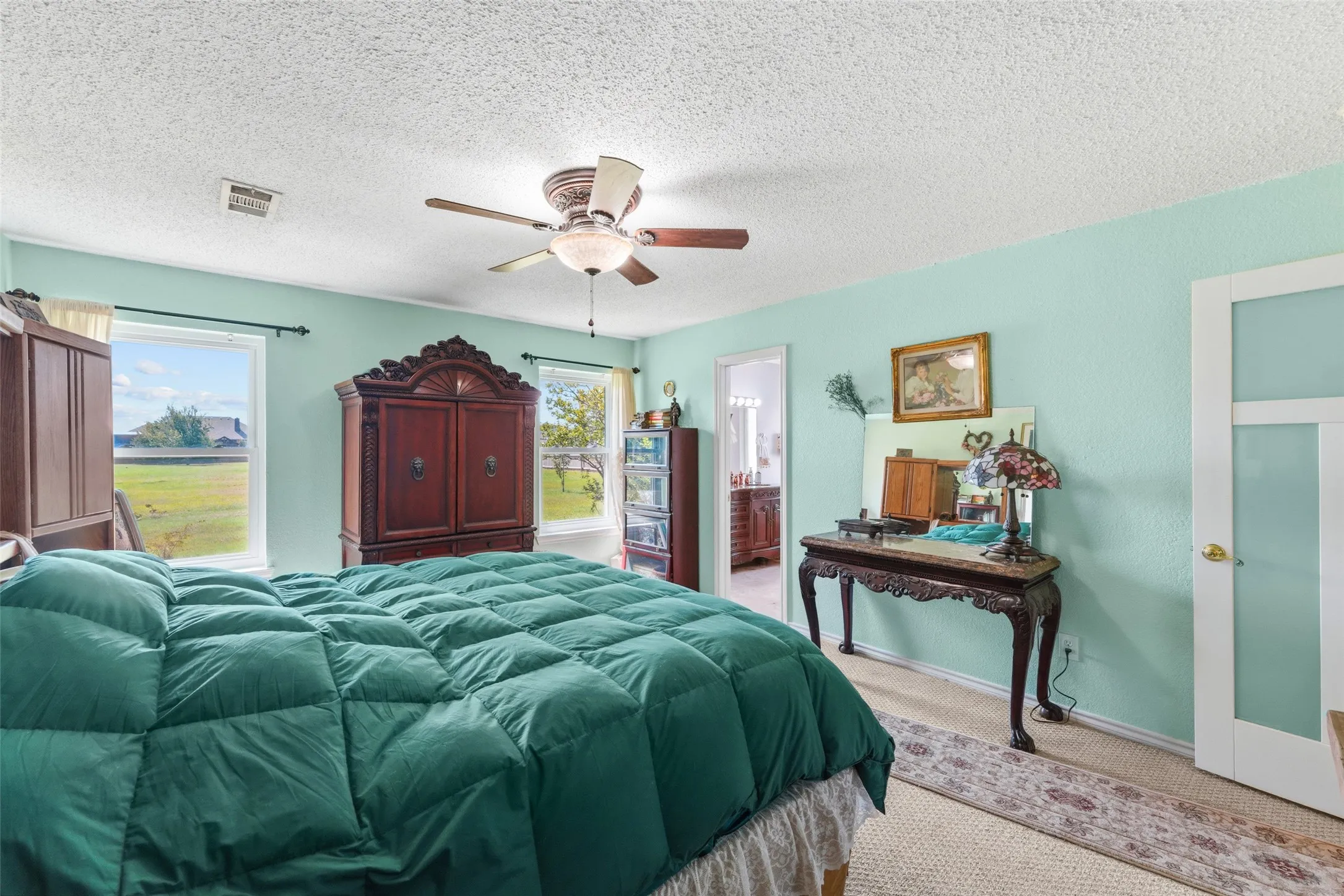 Bright interior featuring a ceiling fan with integrated lighting, two windows with exterior views, and a white door with frosted glass panels