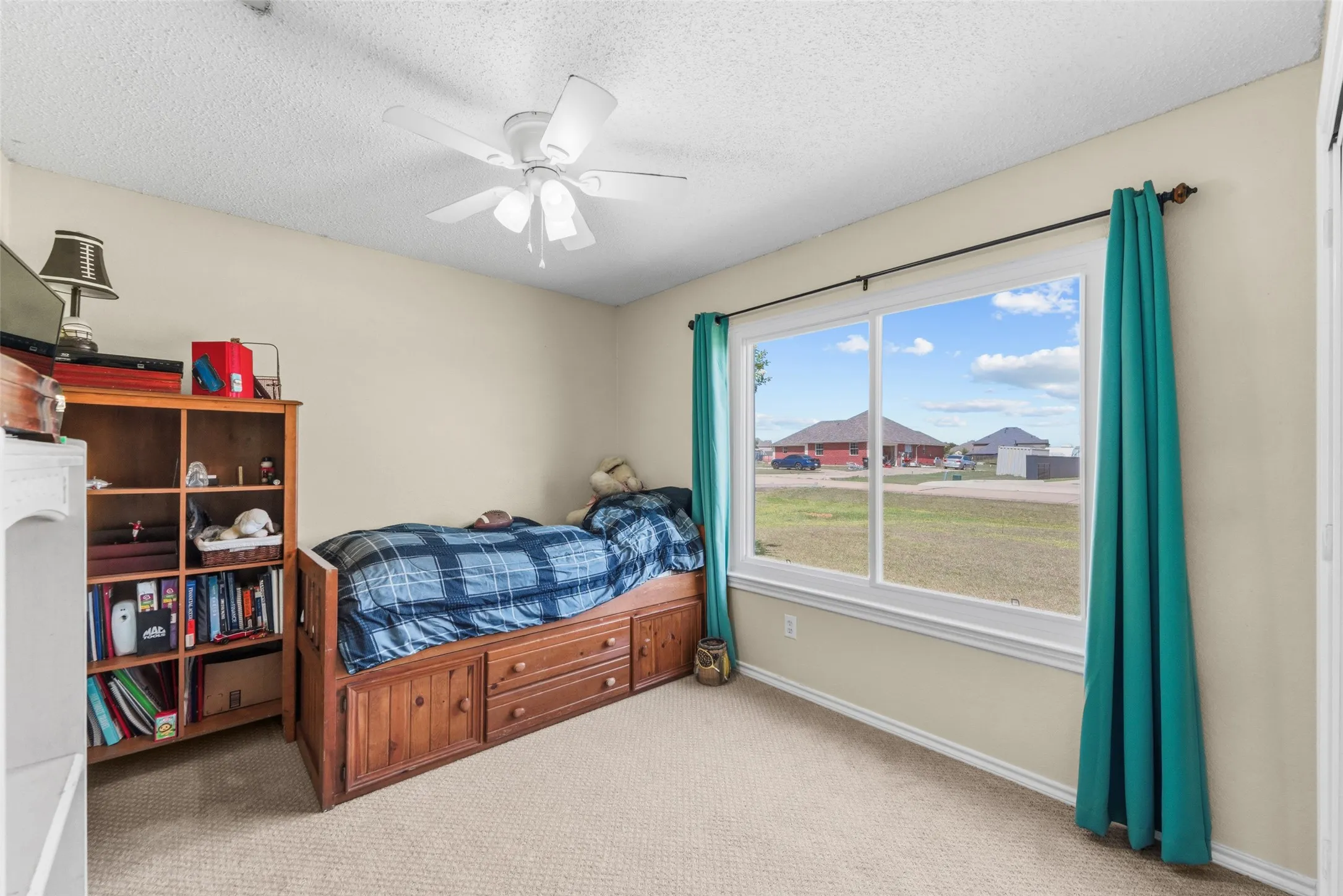 Carpeted room with a large window and a ceiling fan