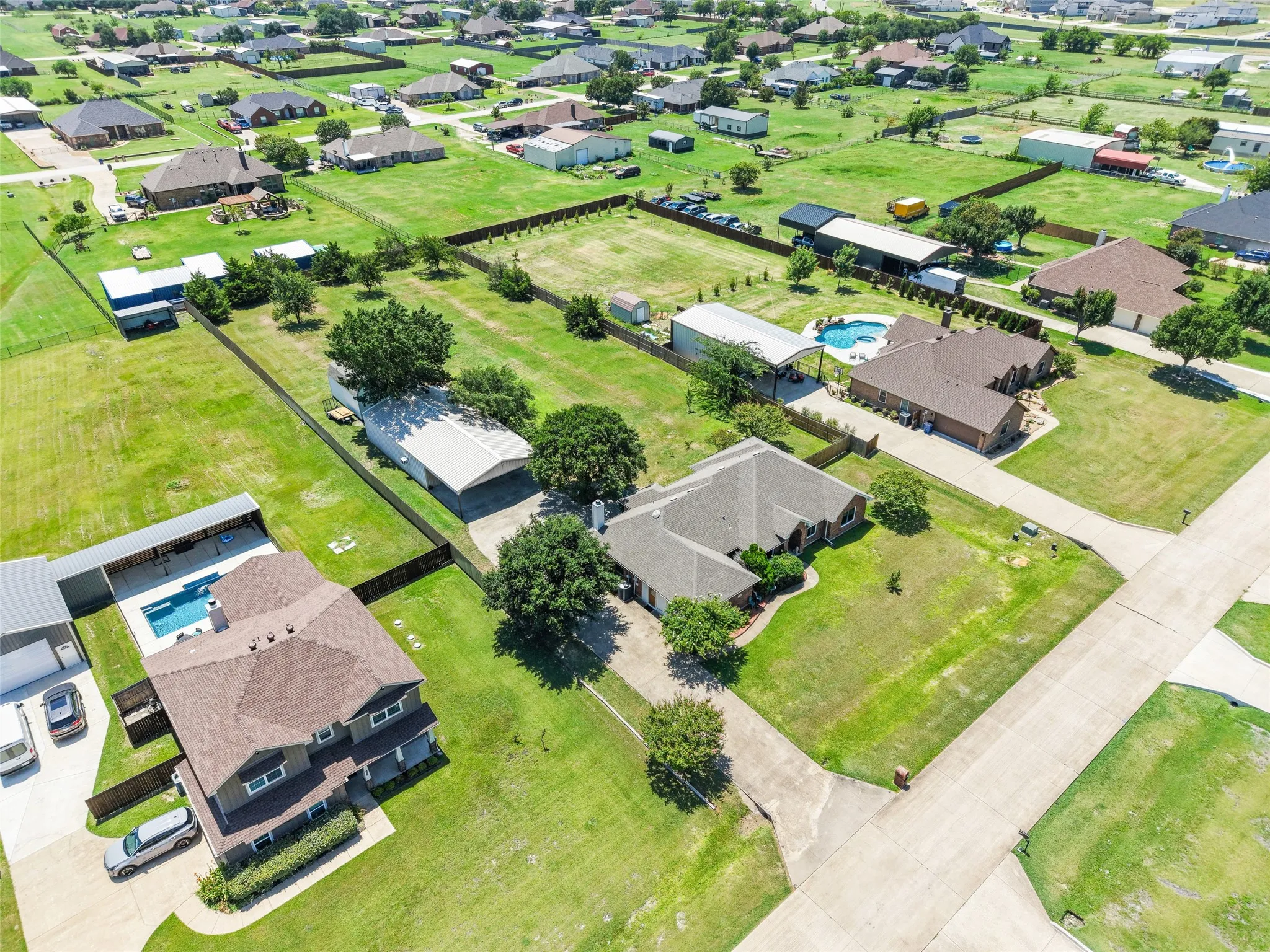 Aerial view of properties featuring expansive green lawns
