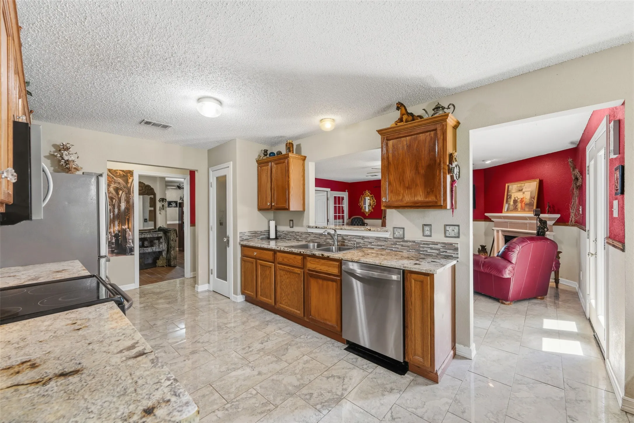 Kitchen featuring granite countertops, wood cabinetry, stainless steel appliances, and tile flooring